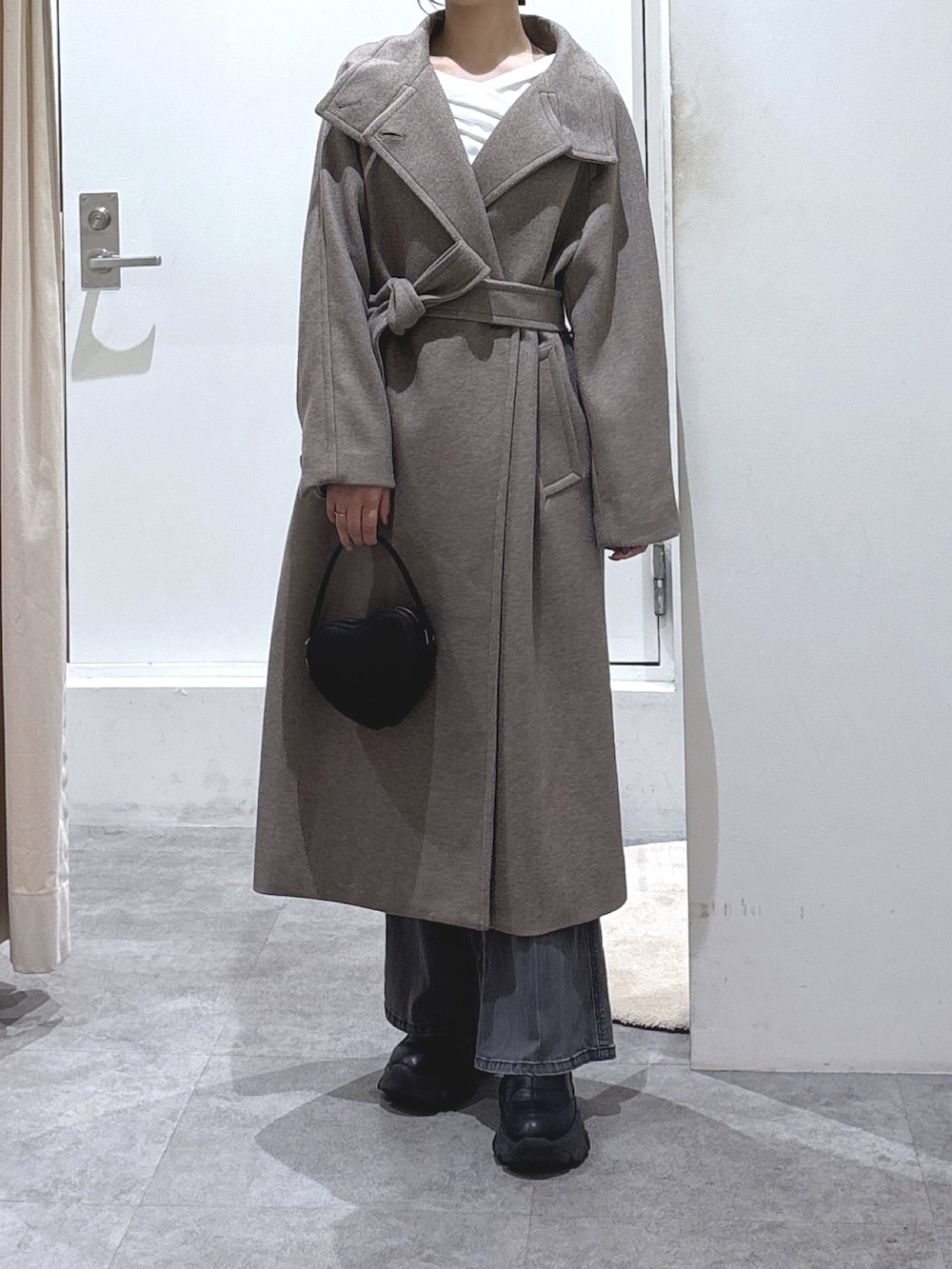 ブラウン系のステンカラーコート、ブラック系のデニムパンツ、ブラック系のショルダーバッグを着用したレディースの冬コーディネートの2枚目の写真