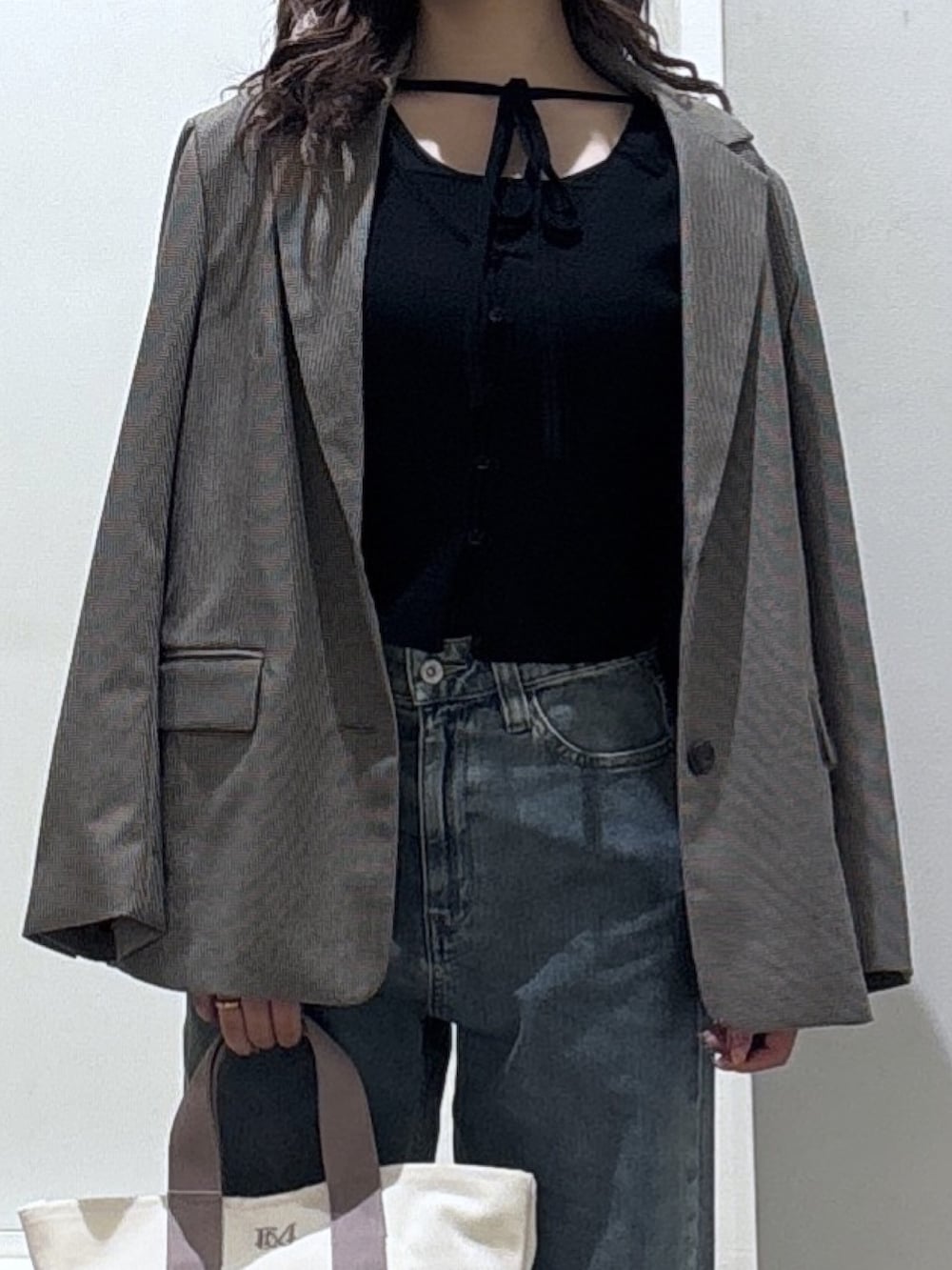 ベージュ系のテーラードジャケット、ブルー系のデニムパンツ、ブラック系のニット/セーターを着用したレディースの冬コーディネートの2枚目の写真