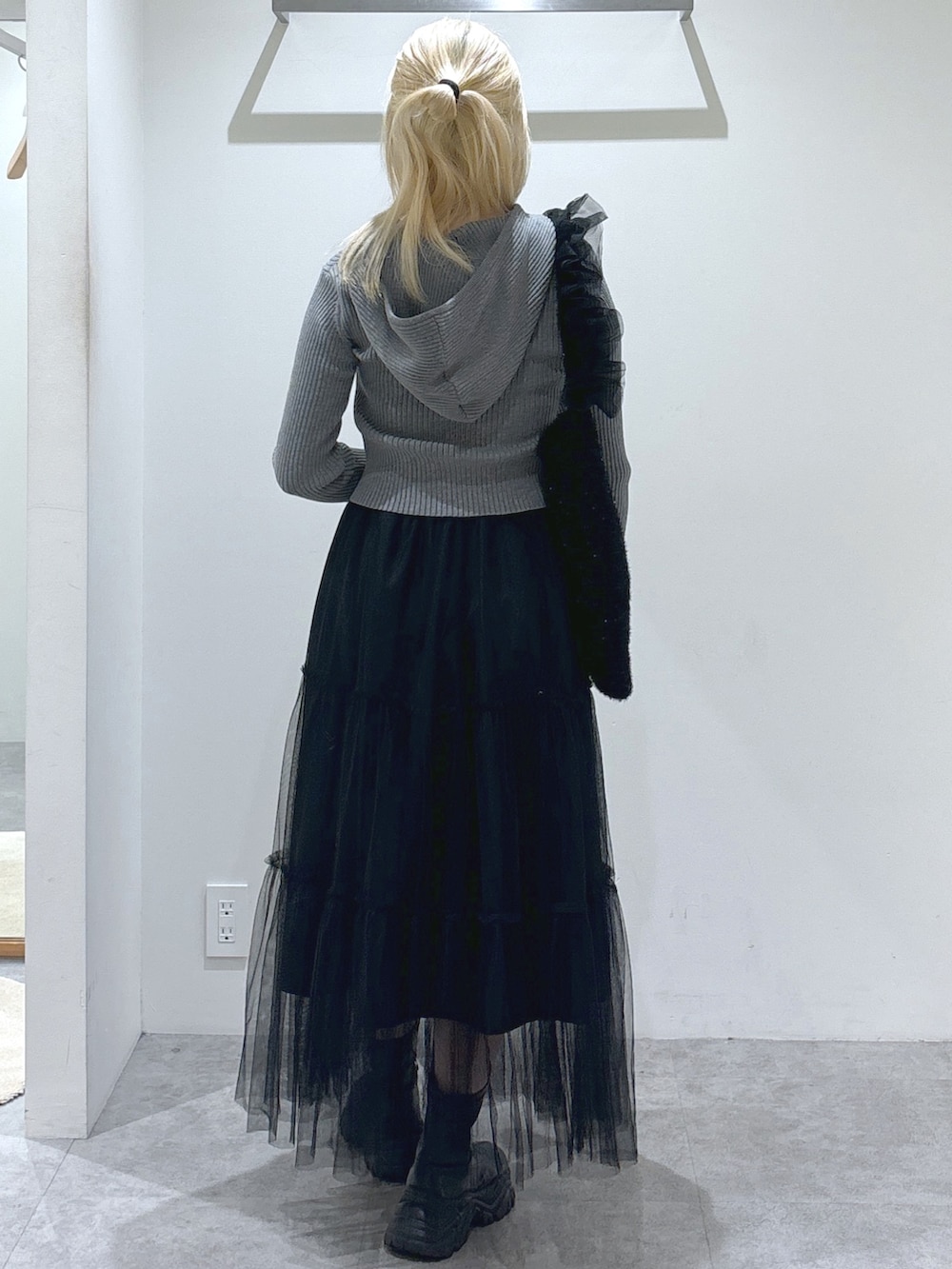 グレー系のニット/セーター、ブラック系のスカート、ブラック系のショルダーバッグを着用したレディースの秋コーディネートの3枚目の写真