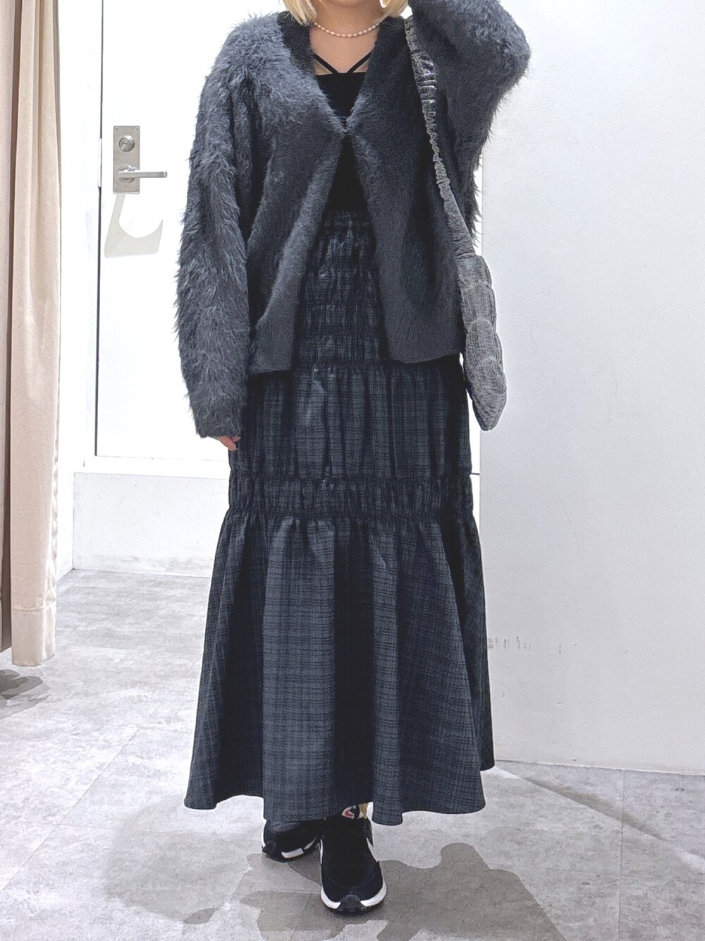 グレー系のスカート、グレー系のカーディガン/ボレロ、ブラック系のキャミソールを着用したレディースの冬コーディネートの2枚目の写真