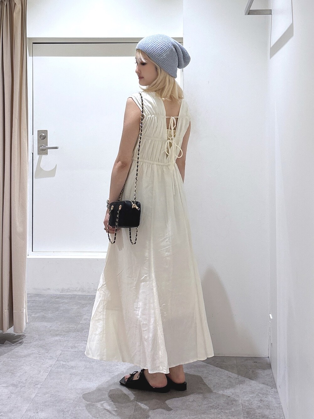 ホワイト系のワンピース、ブラック系のショルダーバッグを着用したレディースの夏コーディネートの3枚目の写真