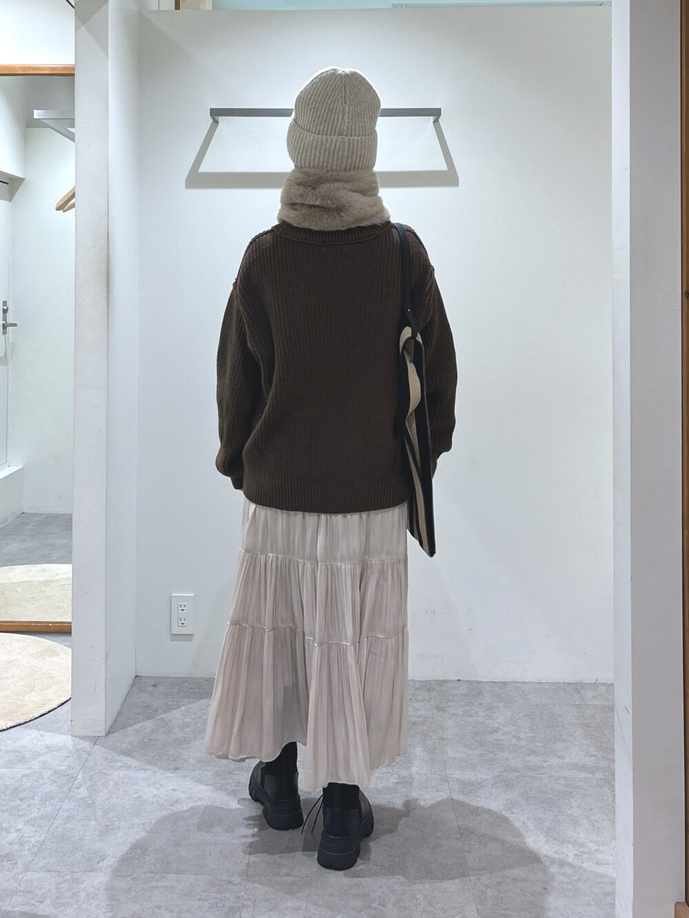 ブラウン系のニット/セーター、ホワイト系のスカート、ブラック系のショルダーバッグを着用したレディースの秋コーディネートの4枚目の写真