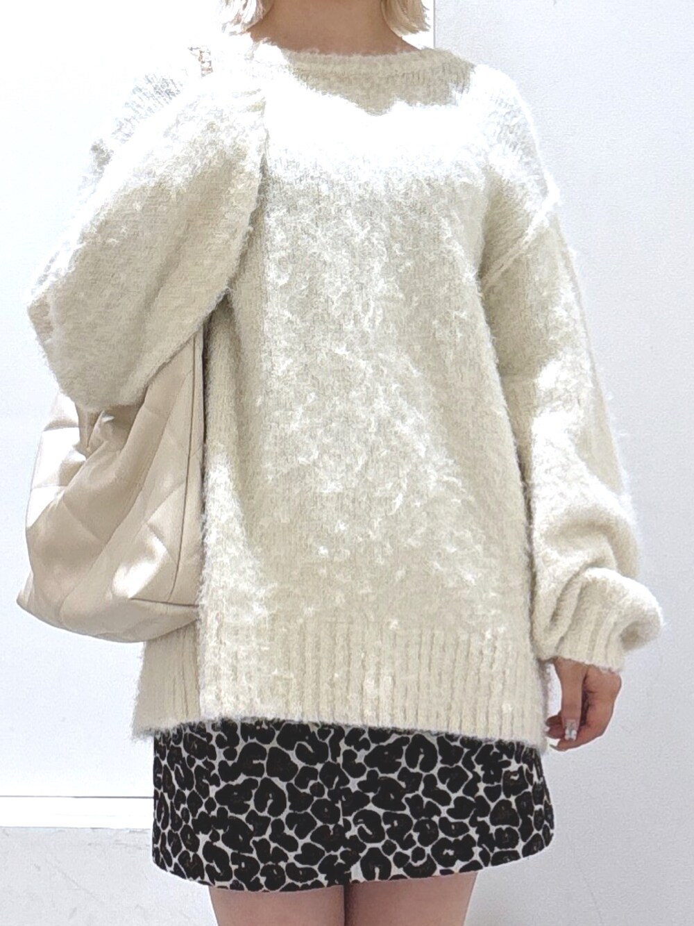 ホワイト系のニット/セーター、ブラウン系のスカート、ブラック系のブーツを着用したレディースの冬コーディネートの2枚目の写真