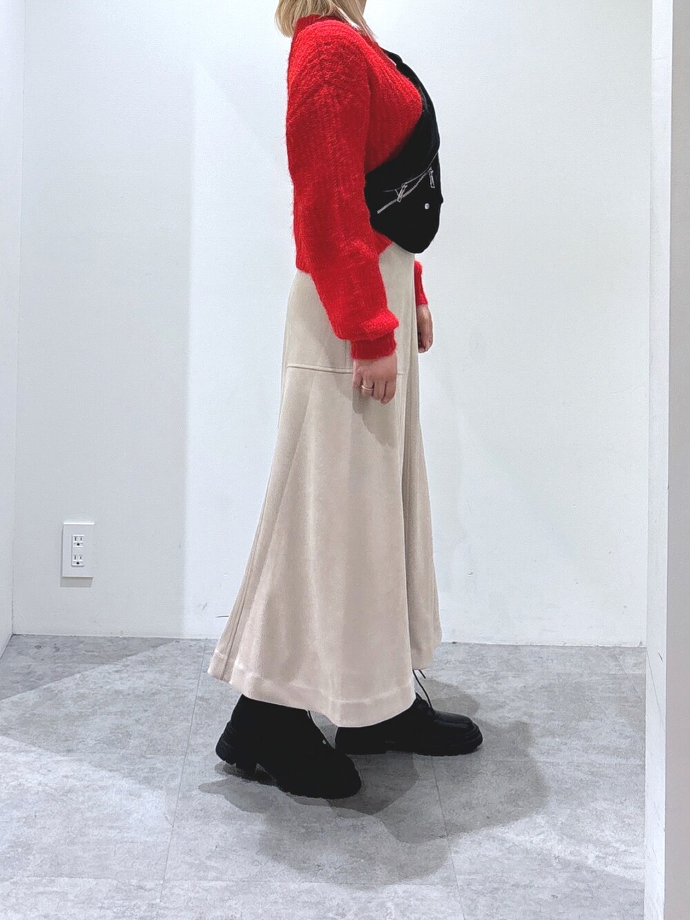 レッド系のニット/セーター、ベージュ系のスカートを着用したレディースの秋コーディネートの3枚目の写真