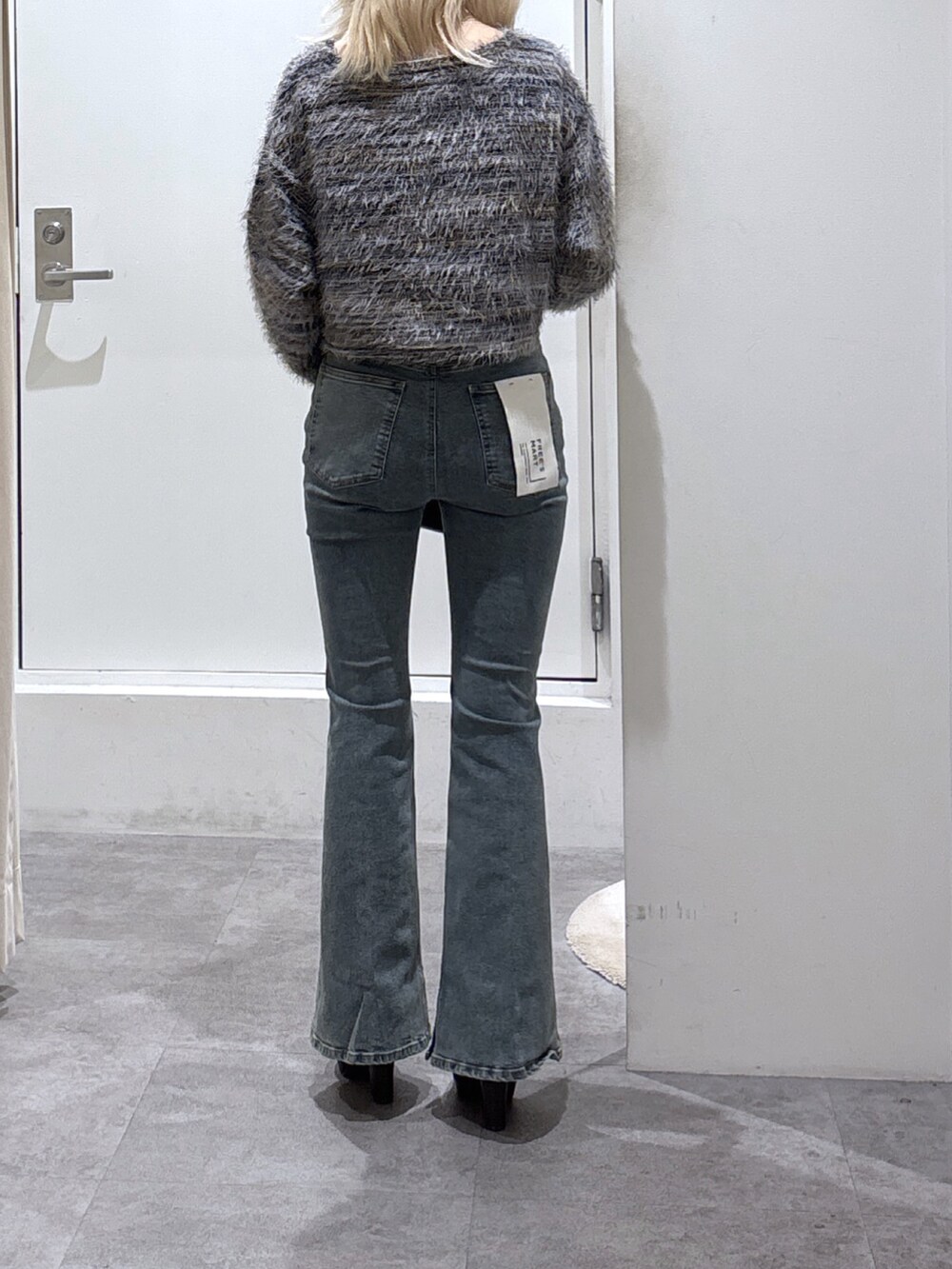 グレー系のニット/セーター、ブルー系のデニムパンツ、ブラック系のハンドバッグを着用したレディースの秋コーディネートの3枚目の写真