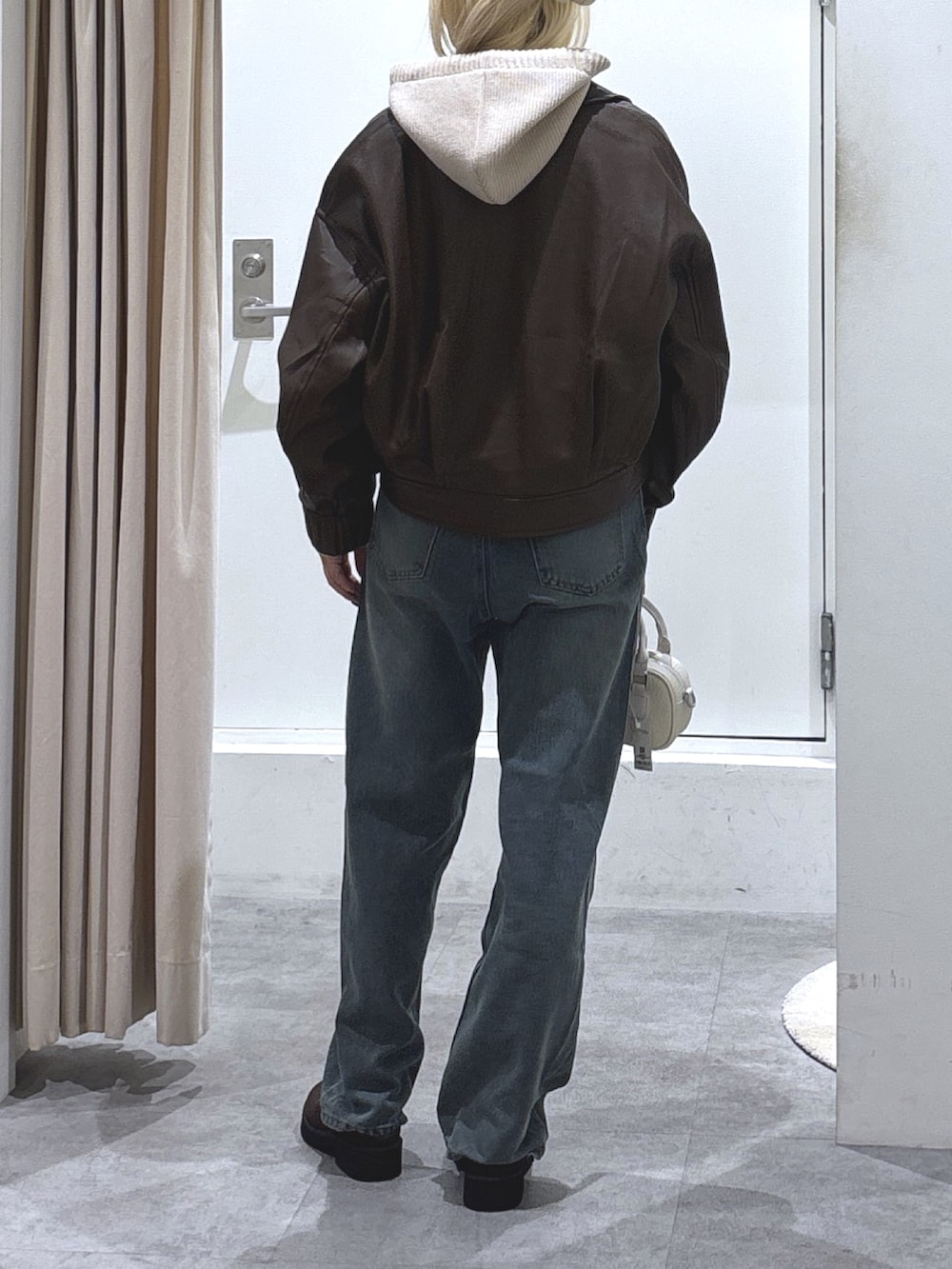 ブラウン系のブルゾン、ベージュ系のニット/セーター、ブルー系のデニムパンツを着用したレディースの秋コーディネートの2枚目の写真