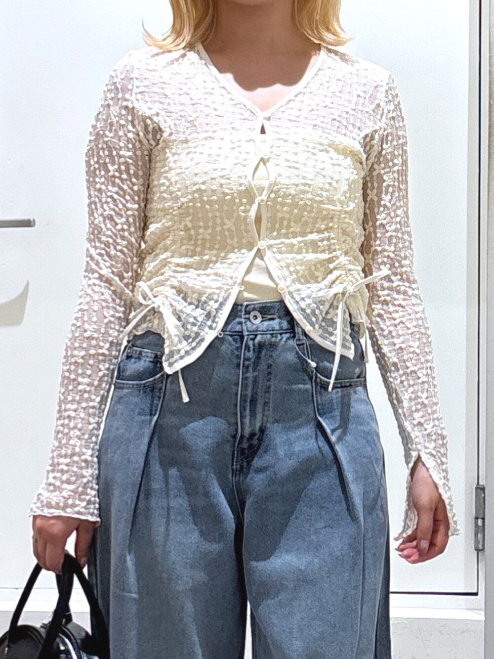 ホワイト系のカーディガン/ボレロ、ブルー系のデニムパンツ、ホワイト系のスニーカーを着用したレディースの春コーディネートの2枚目の写真