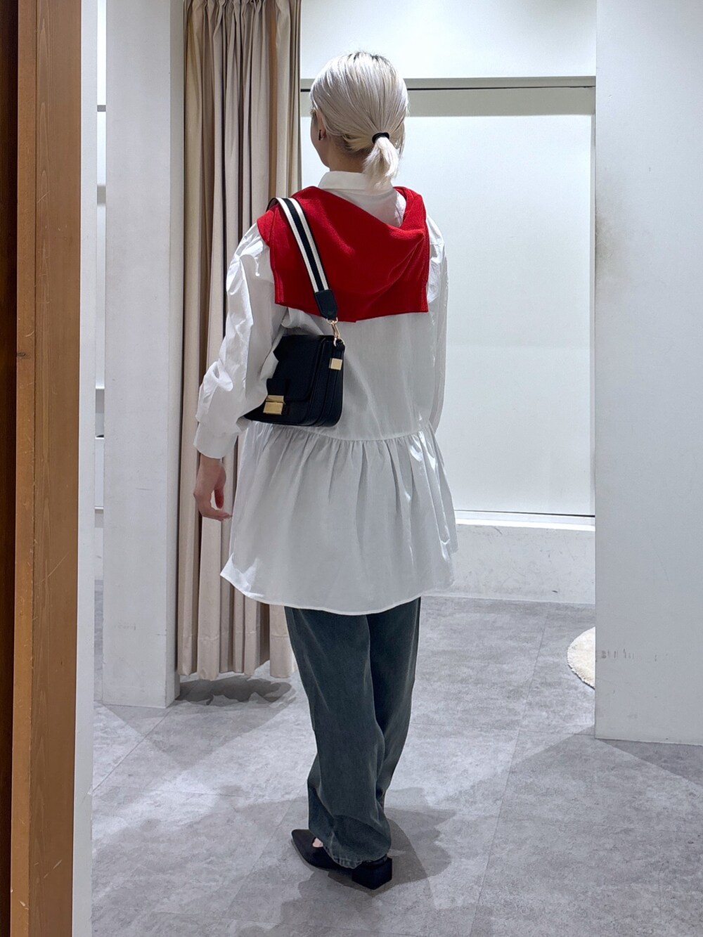 ブルー系のデニムパンツ、レッド系のカーディガン/ボレロ、ホワイト系のワンピースを着用したレディースの春コーディネートの2枚目の写真