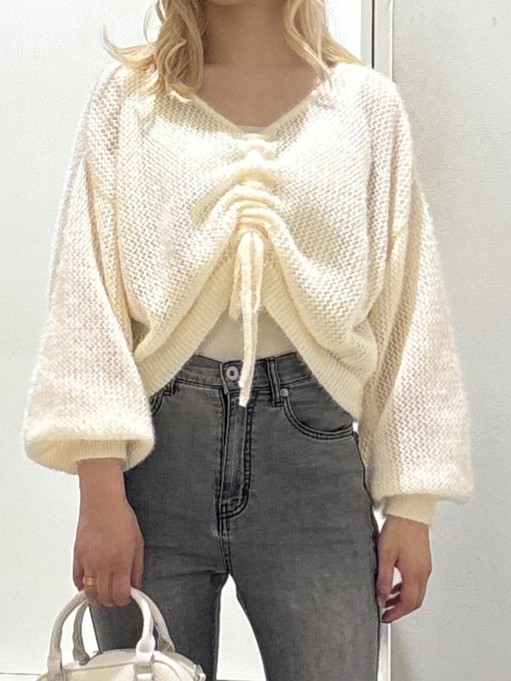 ホワイト系のニット/セーター、ブラック系のデニムパンツを着用したレディースの秋コーディネートの3枚目の写真