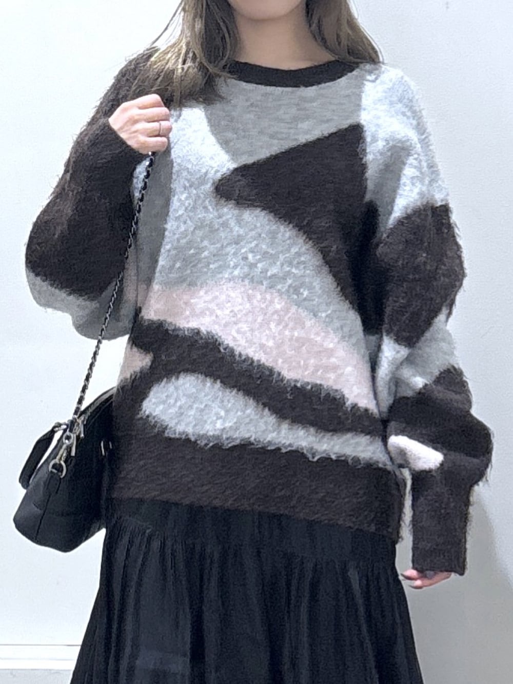 ブラック系のスカート、ブラウン系のニット/セーターを着用したレディースの冬コーディネートの2枚目の写真