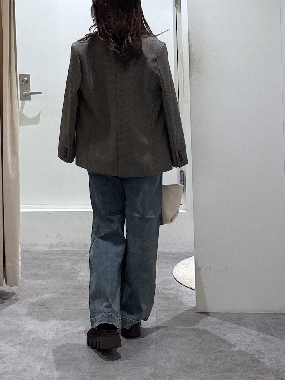 ベージュ系のテーラードジャケット、ブルー系のデニムパンツ、ブラック系のニット/セーターを着用したレディースの冬コーディネートの4枚目の写真