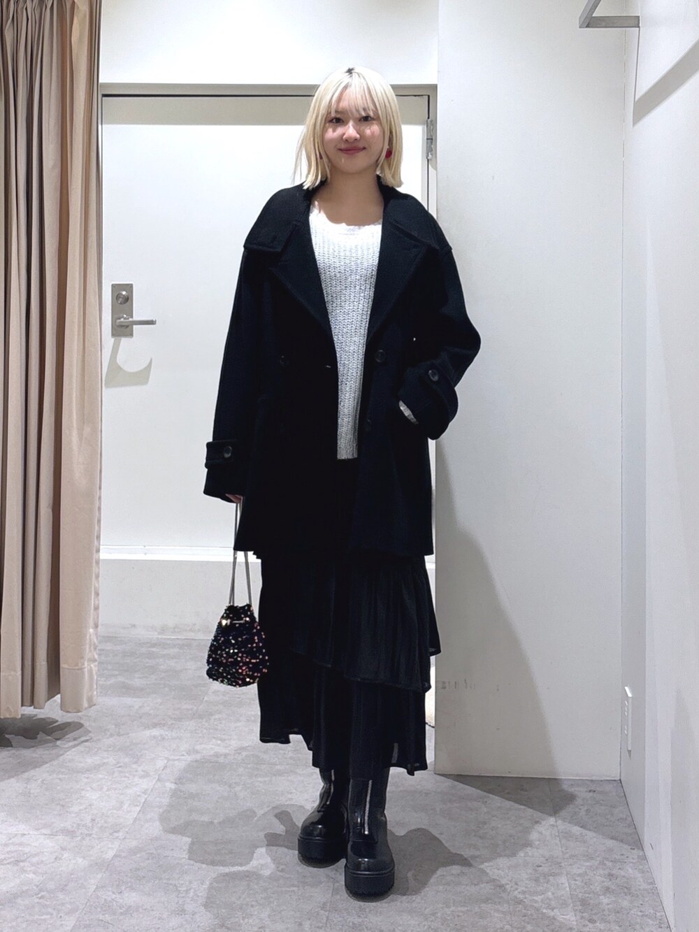 ブラック系のピーコート、ブラック系のショルダーバッグ、ブラック系のスカートを着用したレディースの冬コーディネートの2枚目の写真
