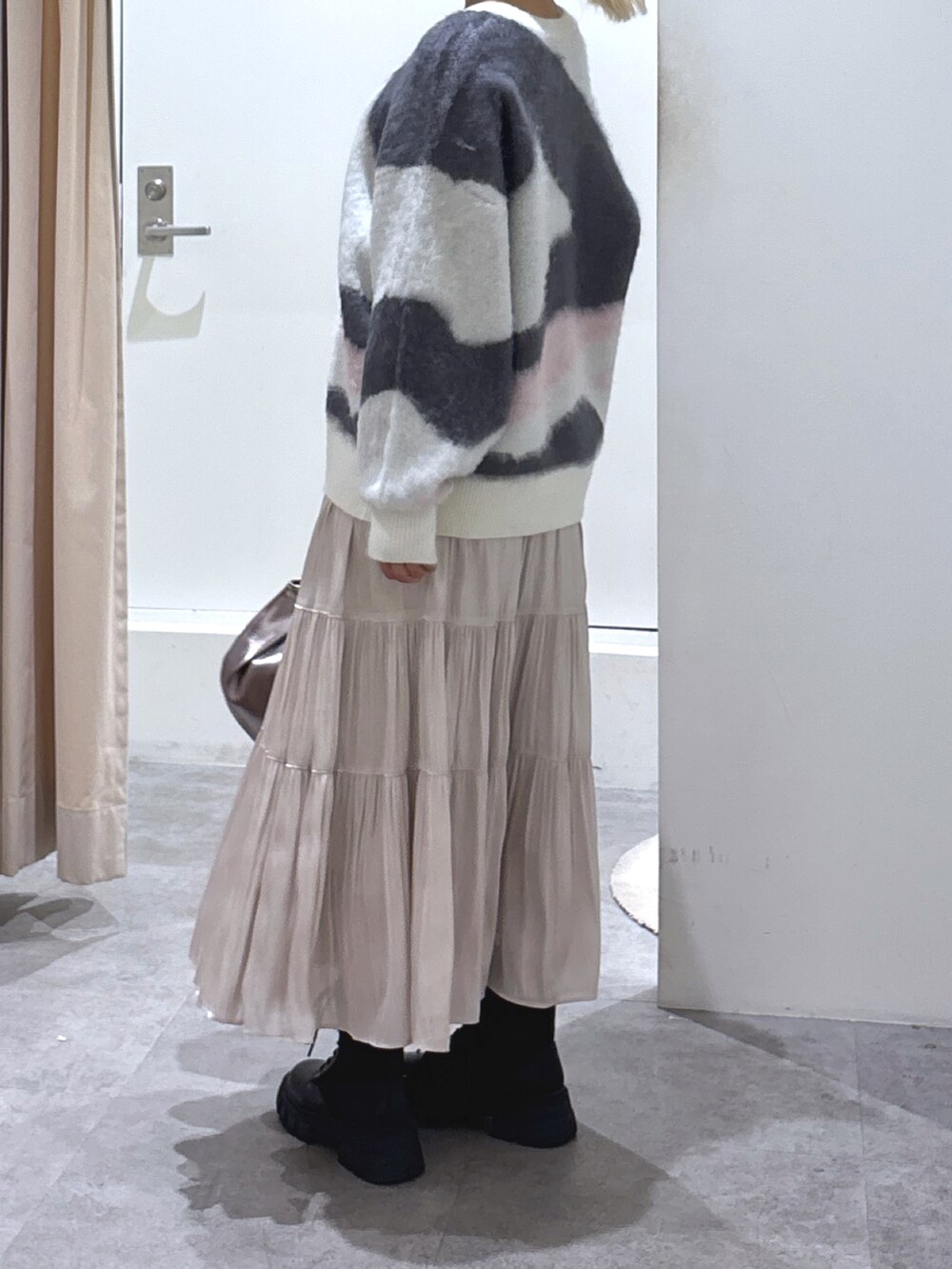 ホワイト系のニット/セーター、ホワイト系のスカート、ブラック系のブーツを着用したレディースの冬コーディネートの5枚目の写真