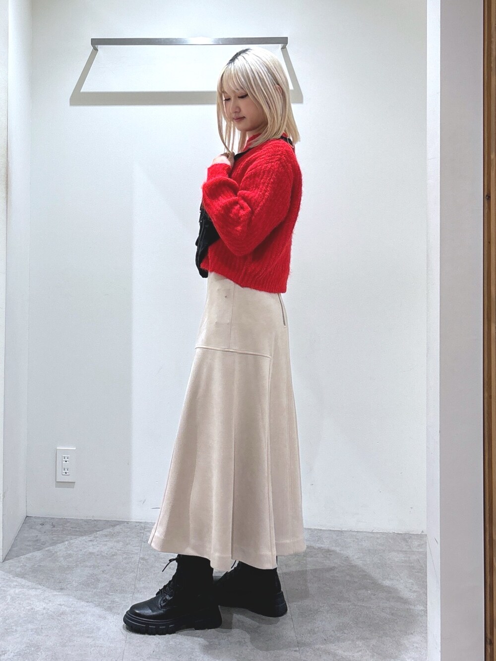 レッド系のニット/セーター、ベージュ系のスカートを着用したレディースの秋コーディネートの2枚目の写真