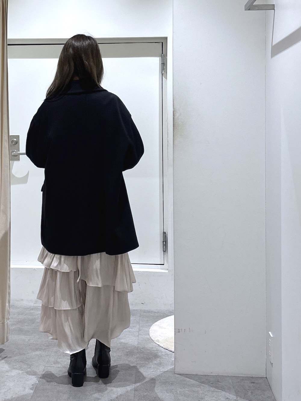 ブラック系のピーコート、ホワイト系のスカート、ブラック系のブーツを着用したレディースの冬コーディネートの3枚目の写真