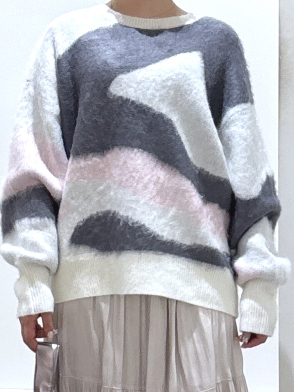 ホワイト系のニット/セーター、ホワイト系のスカート、ブラック系のブーツを着用したレディースの冬コーディネートの2枚目の写真