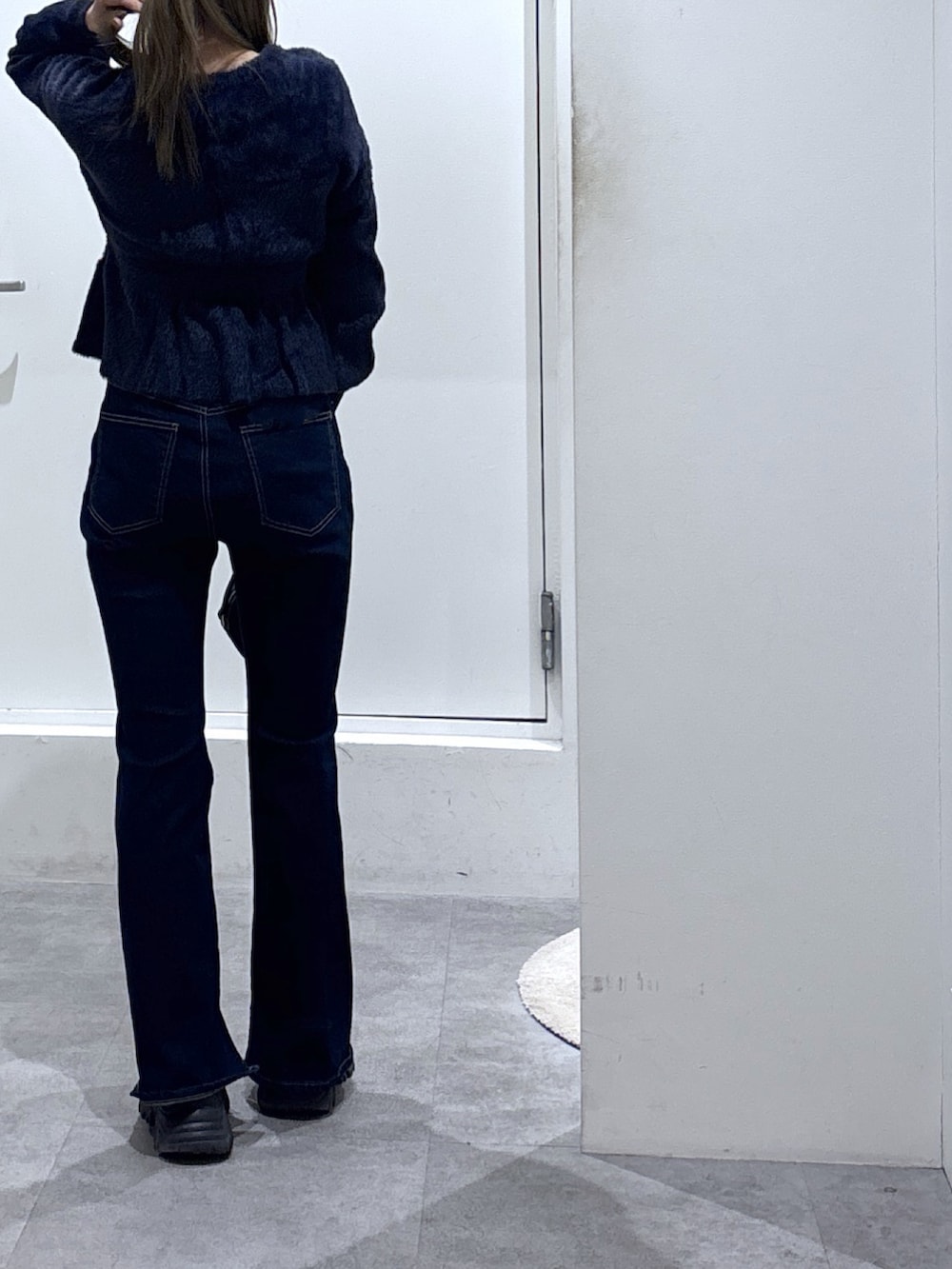 ブルー系のニット/セーター、ブルー系のデニムパンツ、ブラック系のショルダーバッグを着用したレディースの冬コーディネートの2枚目の写真