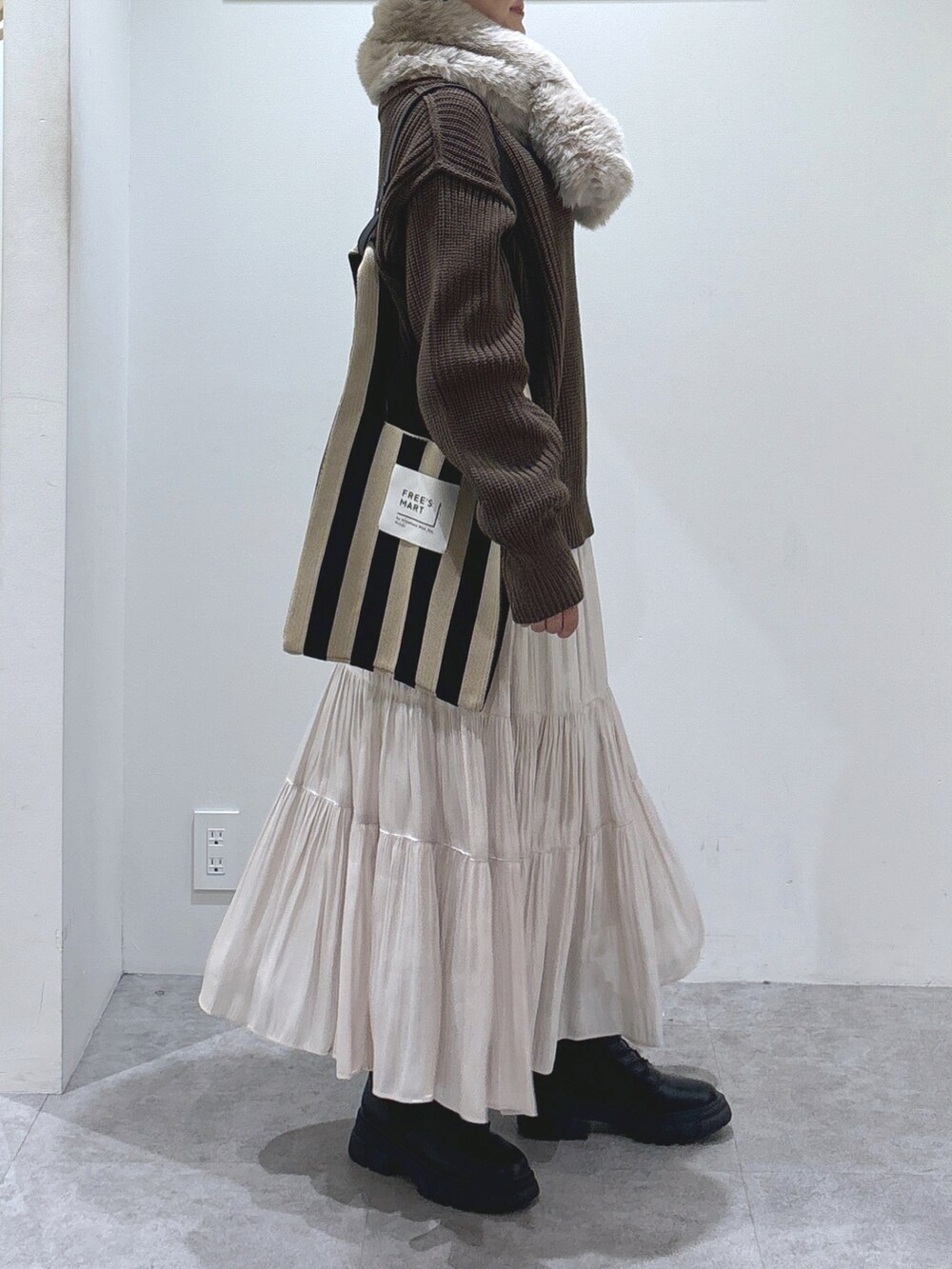 ブラウン系のニット/セーター、ホワイト系のスカート、ブラック系のショルダーバッグを着用したレディースの秋コーディネートの3枚目の写真