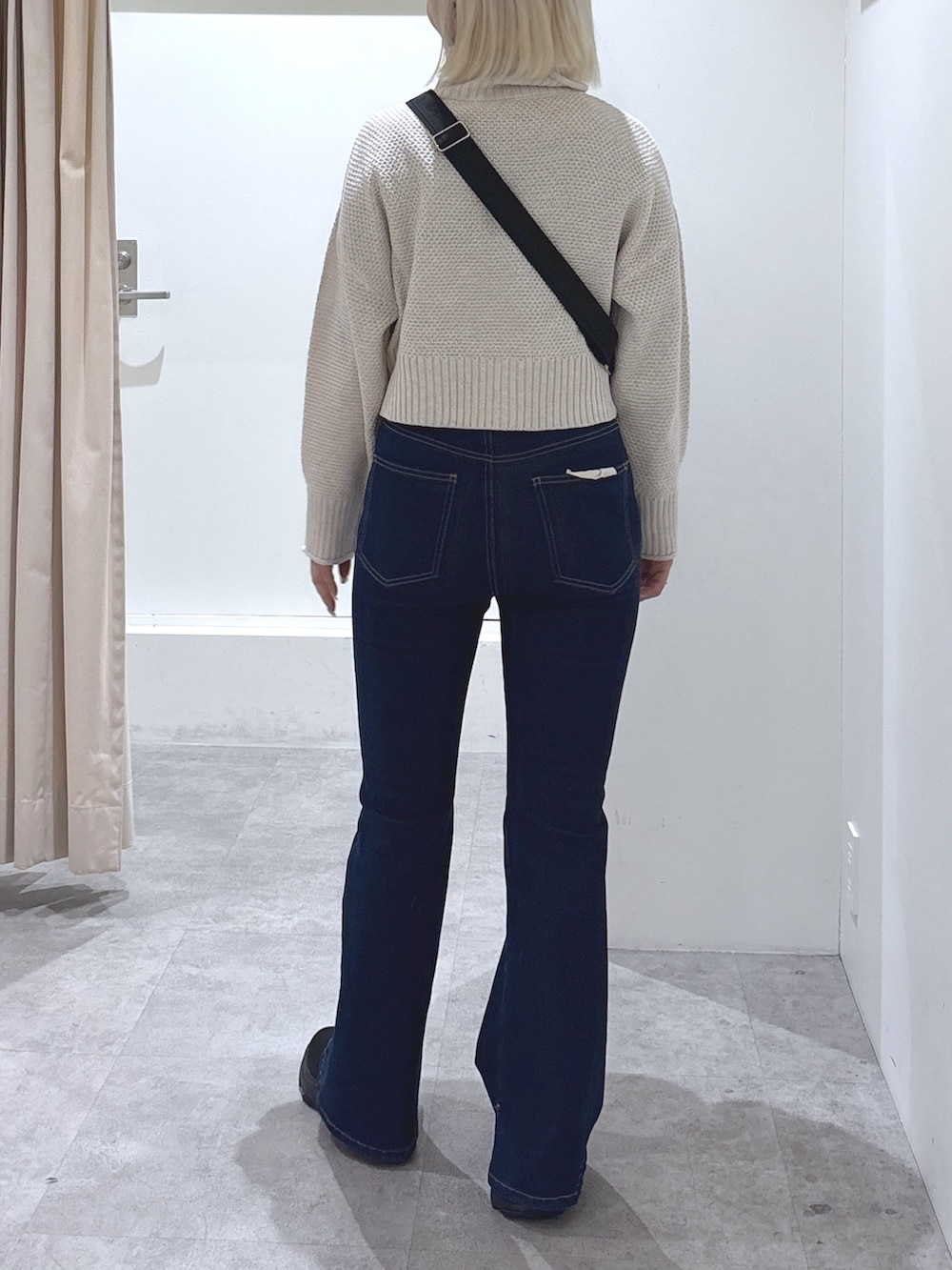 ブラック系のショルダーバッグ、ブルー系のデニムパンツ、ホワイト系のニット/セーターを着用したレディースの冬コーディネートの4枚目の写真