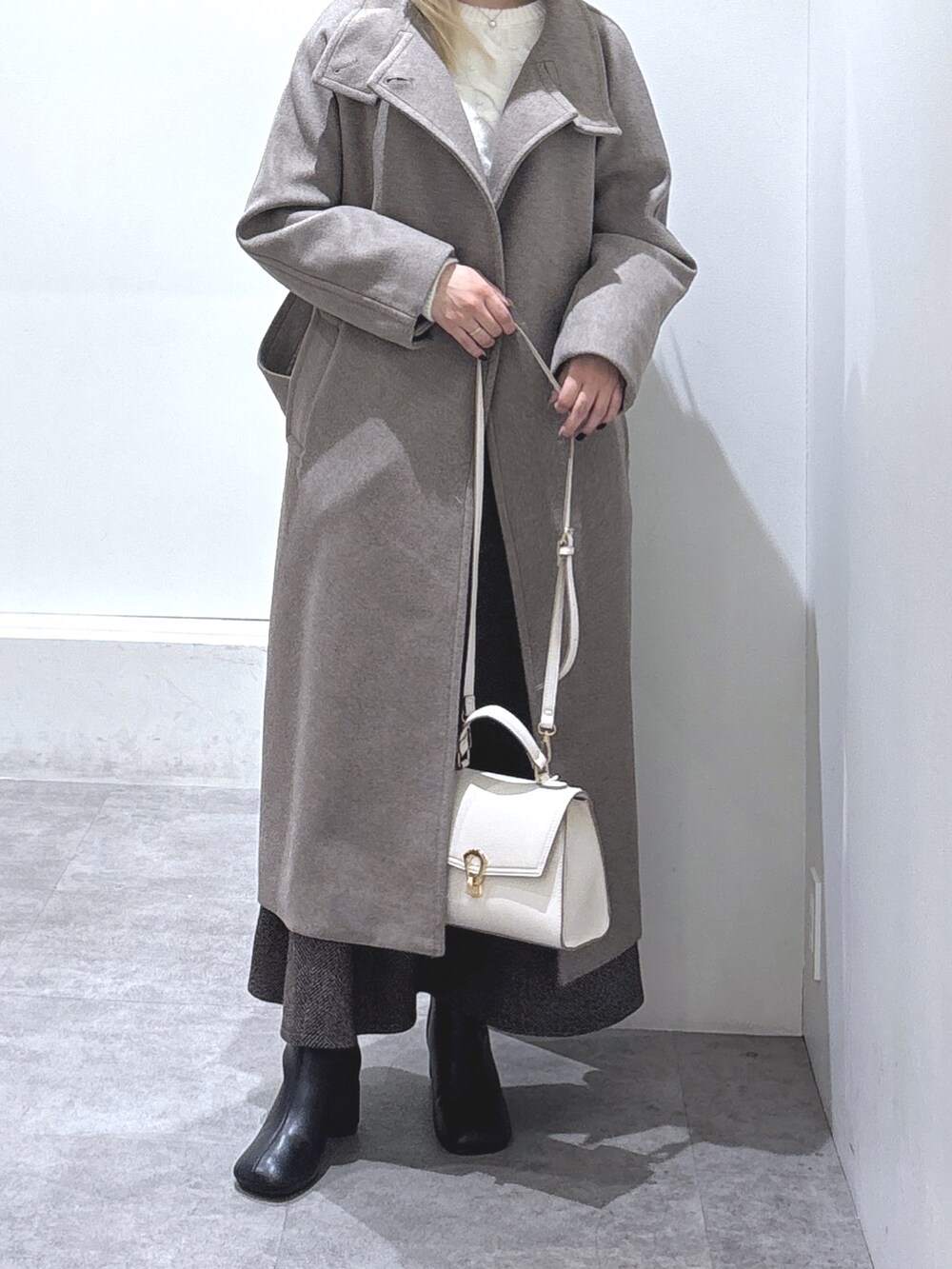 ホワイト系のニット/セーター、ブラウン系のスカート、ブラウン系のステンカラーコートを着用したレディースの秋コーディネートの2枚目の写真