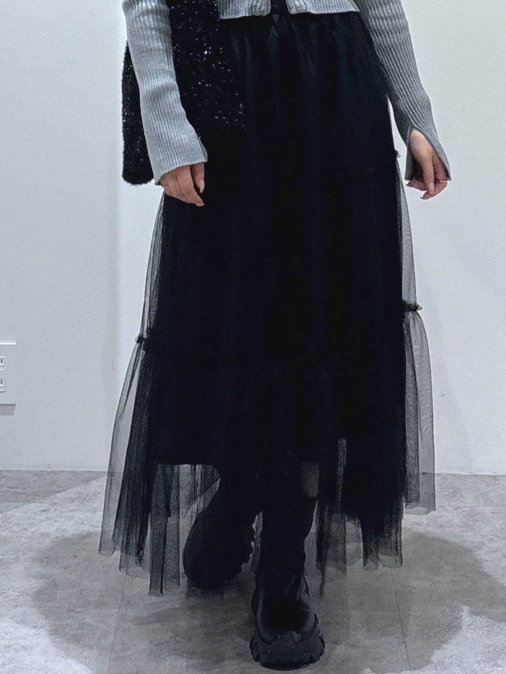 グレー系のニット/セーター、ブラック系のスカート、ブラック系のショルダーバッグを着用したレディースの秋コーディネートの2枚目の写真