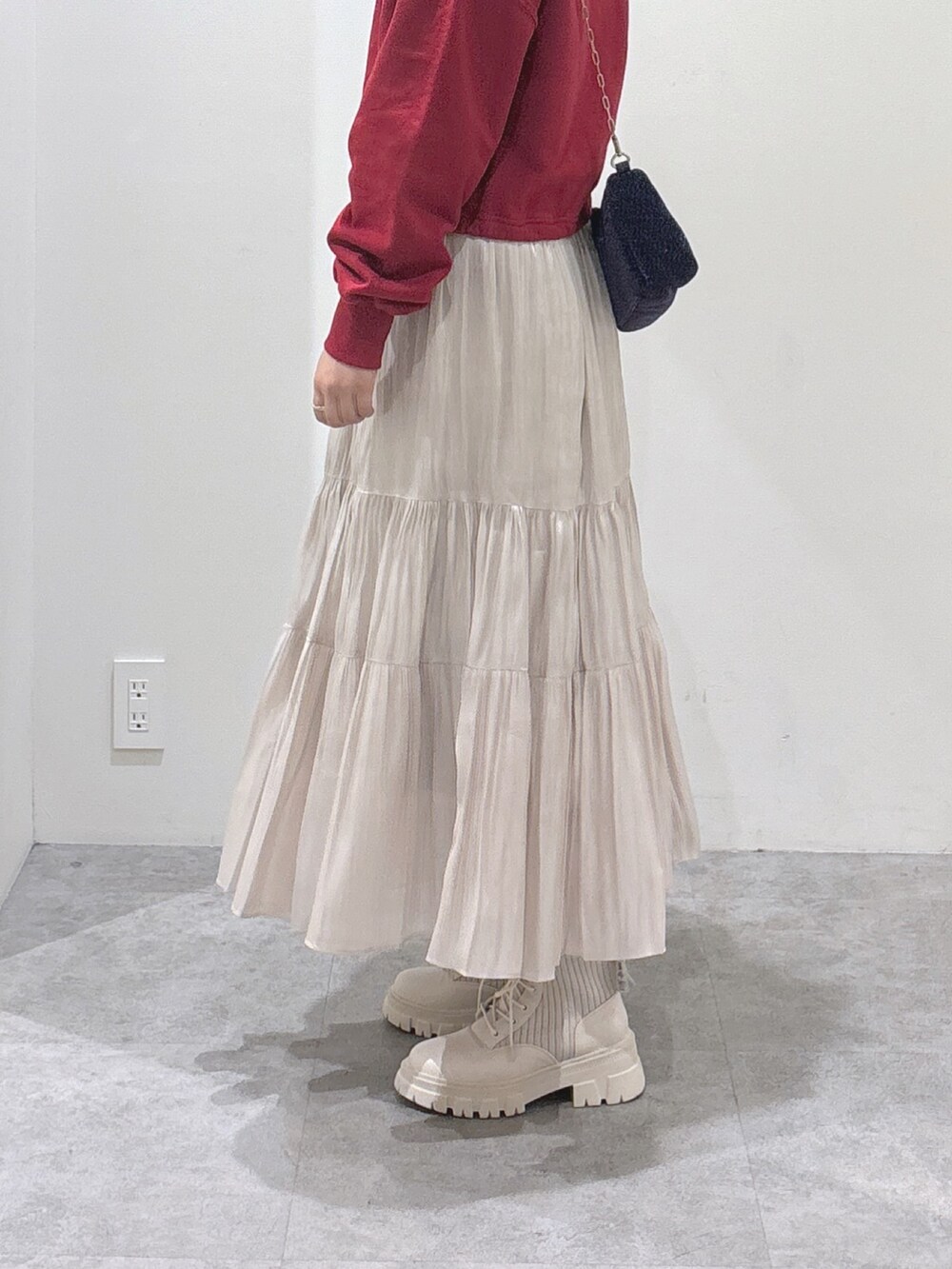 レッド系のTシャツ/カットソー、ホワイト系のスカート、ホワイト系のブーツを着用したレディースの秋コーディネートの3枚目の写真