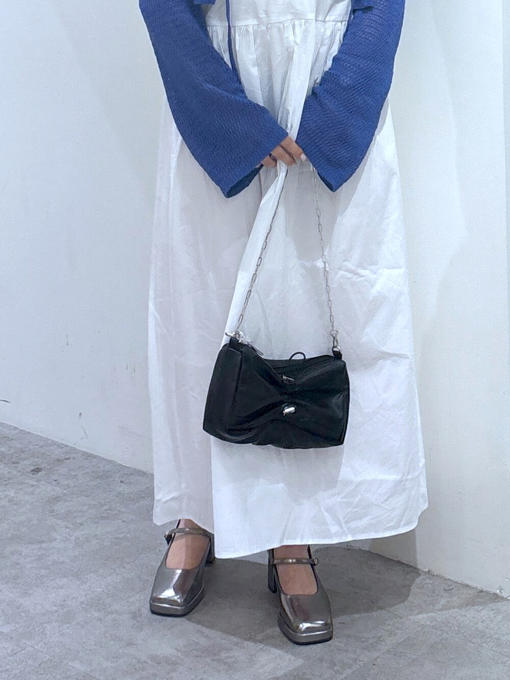 ブルー系のカーディガン/ボレロ、ブラック系のハンドバッグ、ホワイト系のワンピースを着用したレディースの夏コーディネートの3枚目の写真