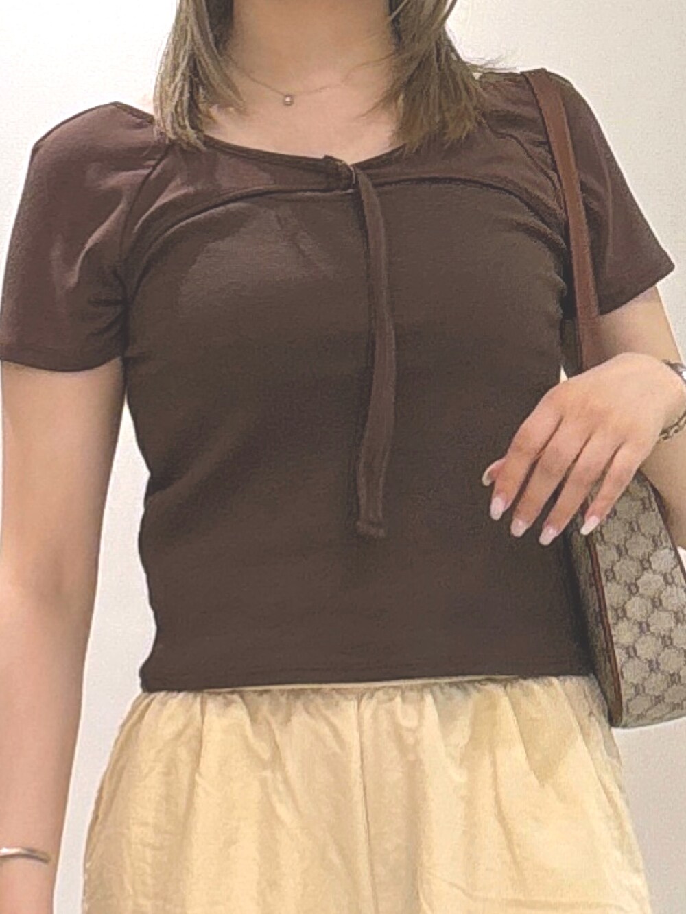 ブラウン系のTシャツ/カットソー、ベージュ系のショルダーバッグ、ゴールド系のパンプスを着用したレディースの夏コーディネートの2枚目の写真