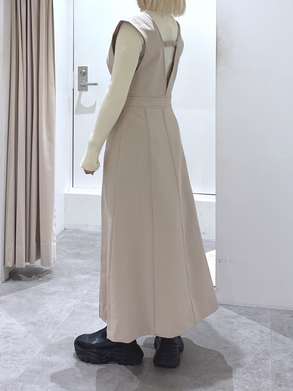 ホワイト系のニット/セーター、ベージュ系のジャンパースカート、ベージュ系のショルダーバッグを着用したレディースの冬コーディネートの2枚目の写真