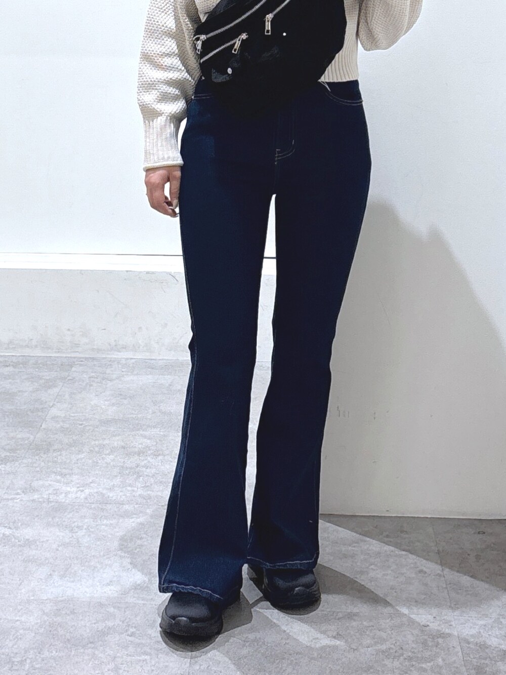 ブラック系のショルダーバッグ、ブルー系のデニムパンツ、ホワイト系のニット/セーターを着用したレディースの冬コーディネートの2枚目の写真