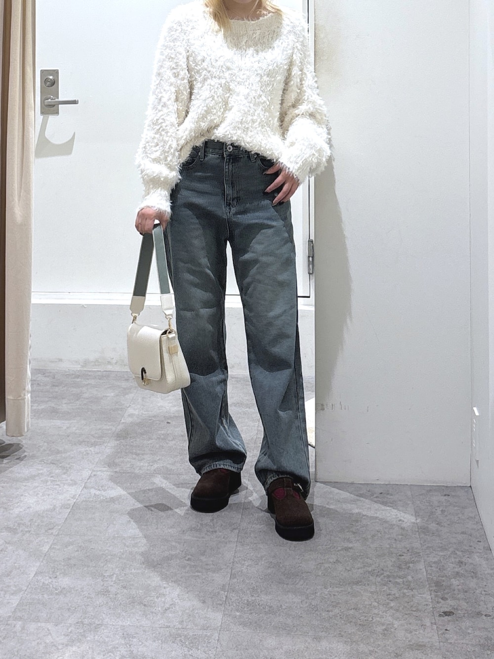 ホワイト系のニット/セーター、ブルー系のデニムパンツを着用したレディースの秋コーディネートの2枚目の写真