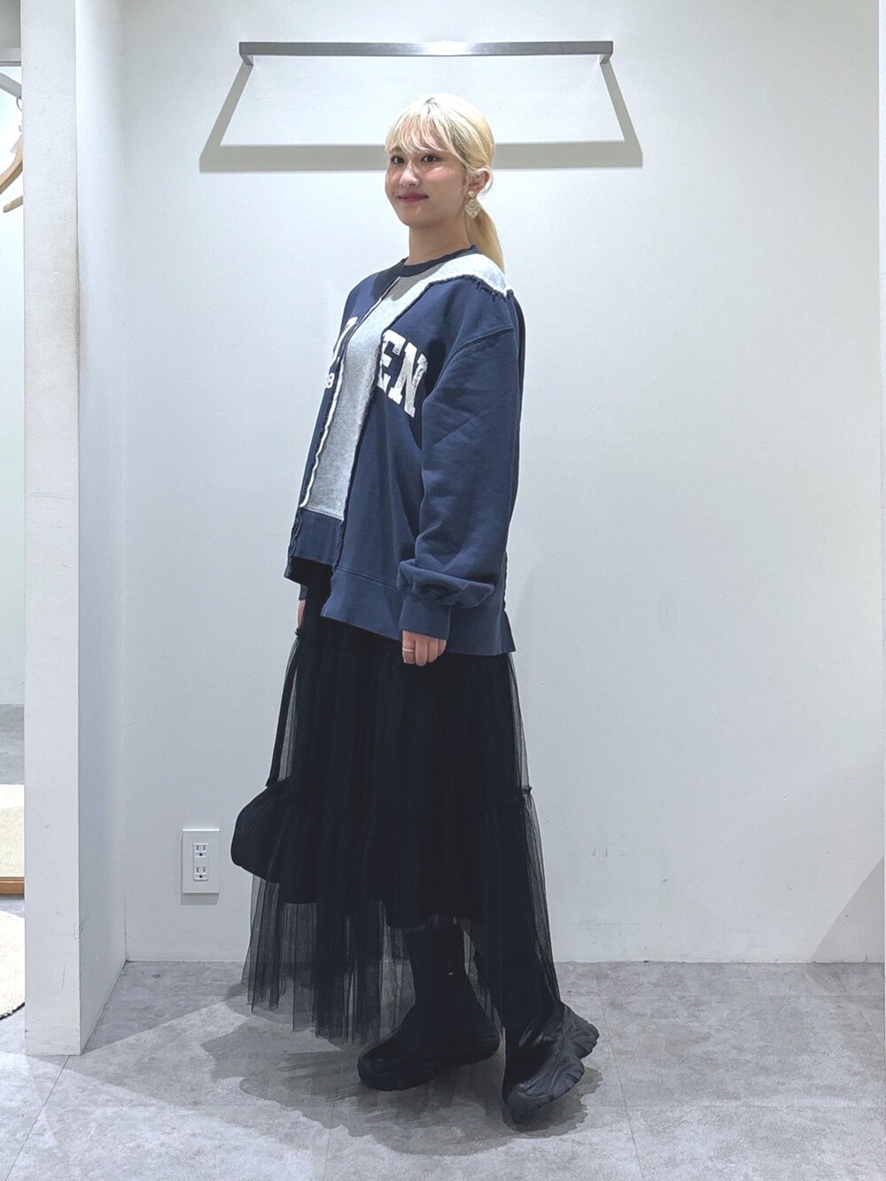 ブルー系のスウェット、ブラック系のスカート、ブラック系のトートバッグを着用したレディースの秋コーディネートの2枚目の写真