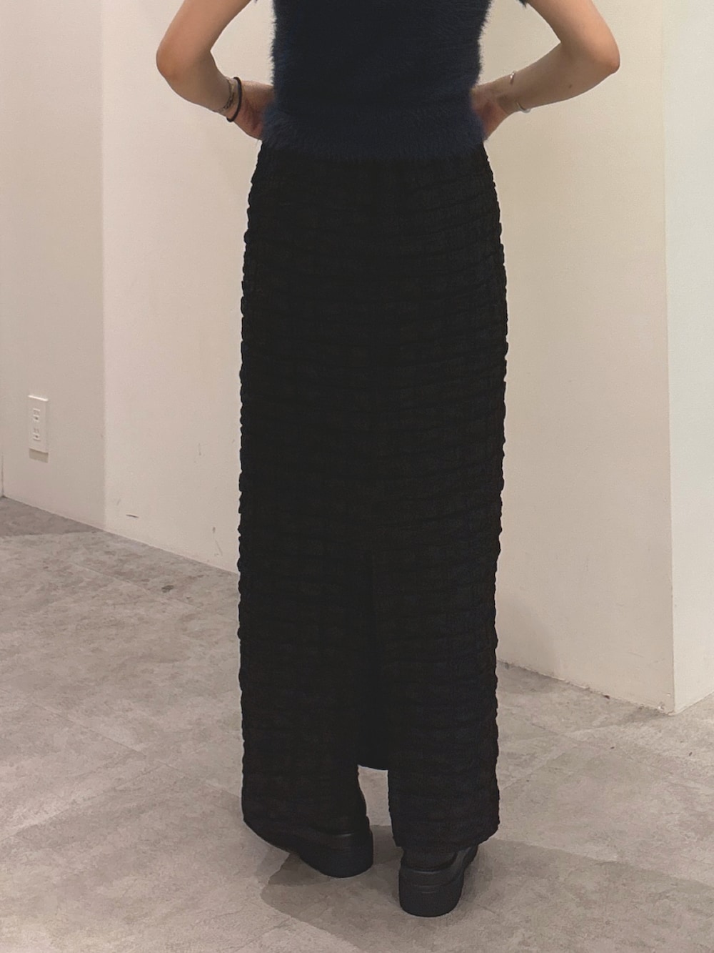 ブルー系のニット/セーター、ブラック系のスカート、ブラック系のブーツを着用したレディースの秋コーディネートの4枚目の写真