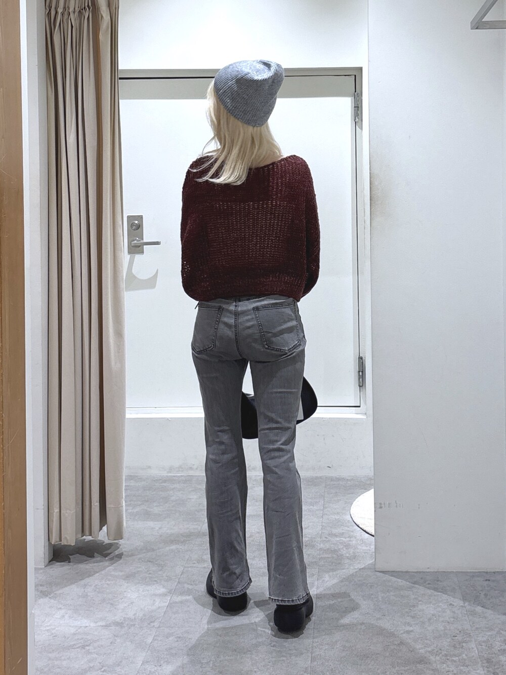 レッド系のニット/セーター、ブラック系のデニムパンツを着用したレディースの秋コーディネートの3枚目の写真