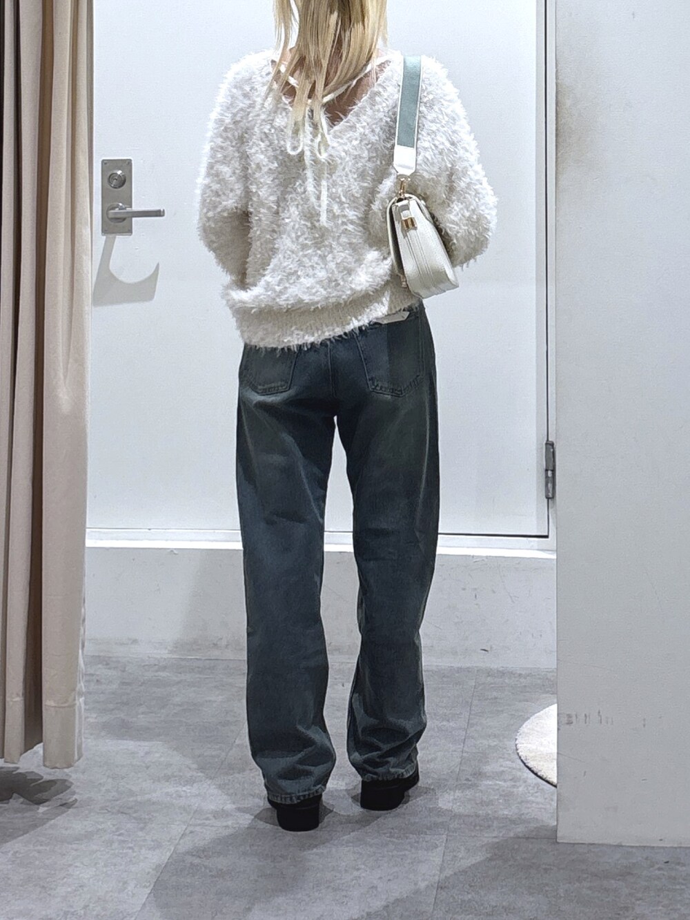 ホワイト系のニット/セーター、ブルー系のデニムパンツを着用したレディースの秋コーディネートの3枚目の写真