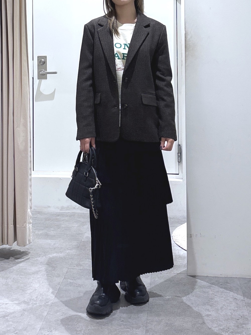 ブラウン系のテーラードジャケット、ブラック系のスカート、ブラック系のトートバッグを着用したレディースの冬コーディネートの2枚目の写真