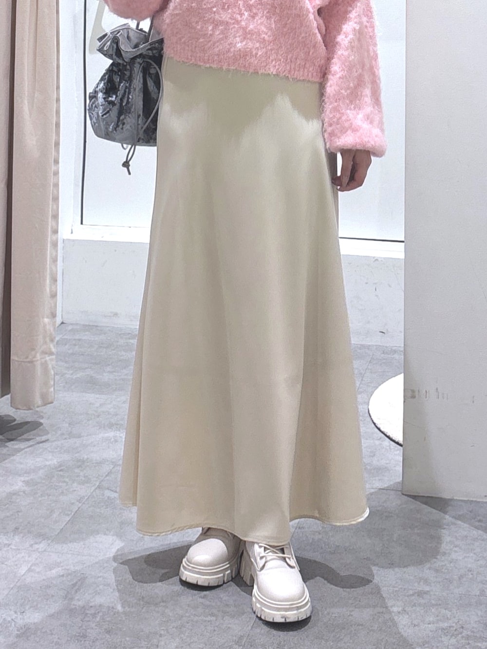 ピンク系のニット/セーター、ベージュ系のスカート、ホワイト系のブーツを着用したレディースの冬コーディネートの2枚目の写真