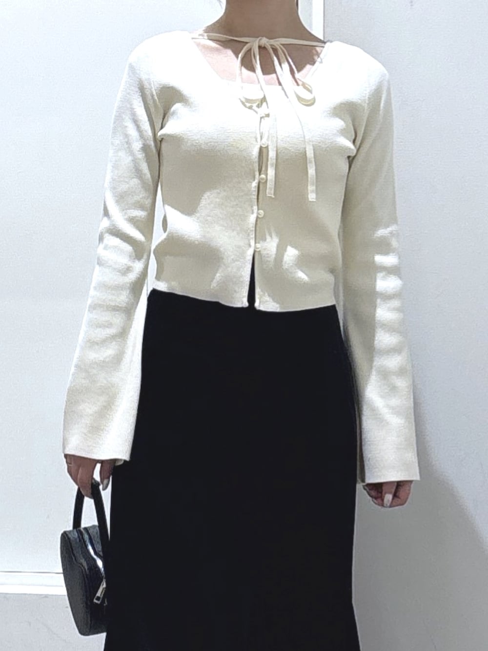 ホワイト系のニット/セーター、ブラック系のスカート、ブラック系のショルダーバッグを着用したレディースの冬コーディネートの2枚目の写真