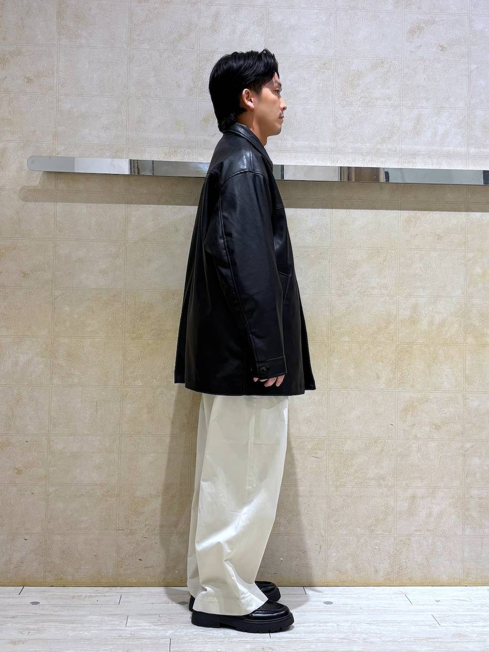 ブラック系のステンカラーコート、ブラック系のドレスシューズ、ホワイト系のチノパンツを着用したメンズの冬コーディネートの5枚目の写真