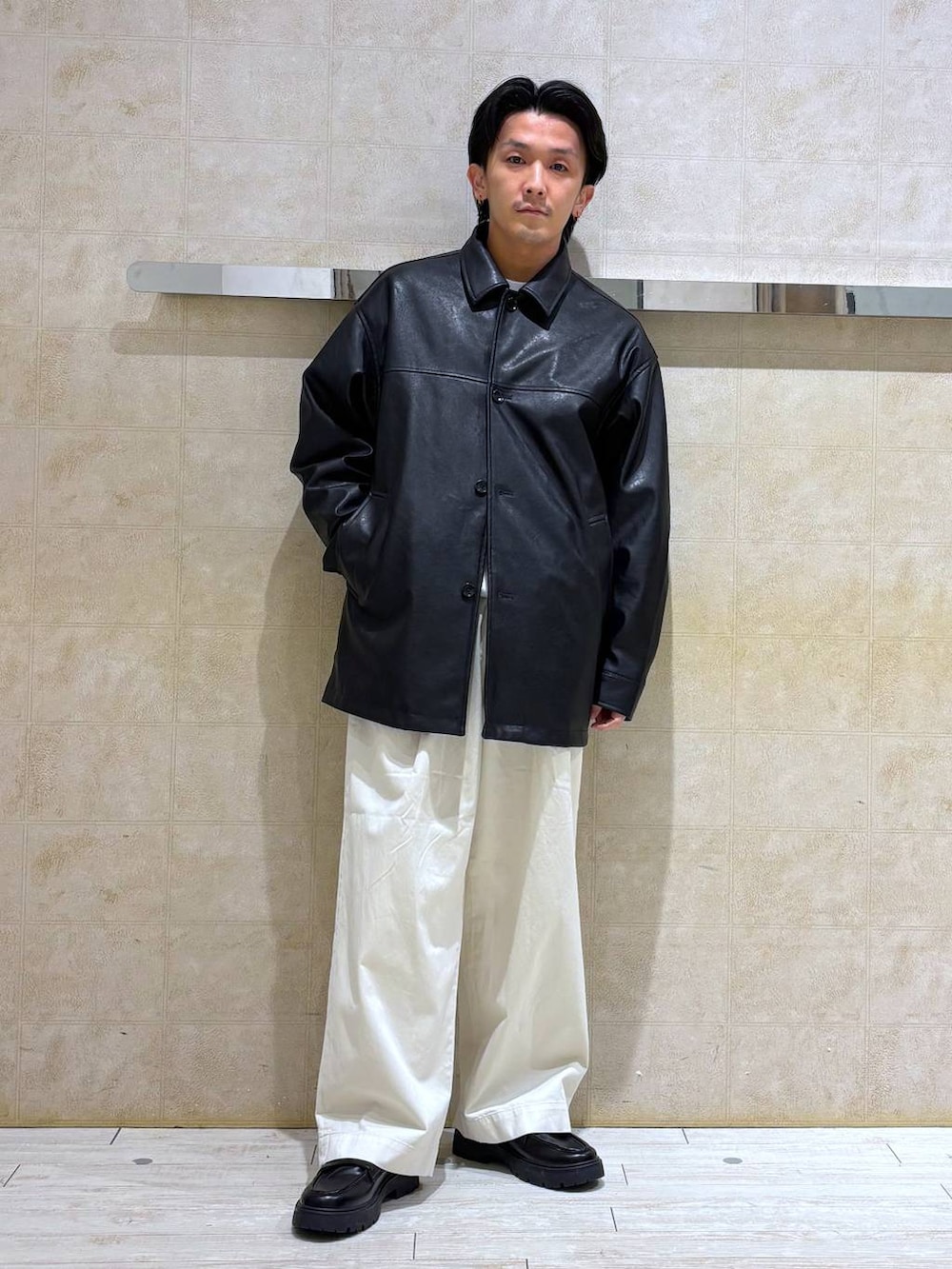 ブラック系のステンカラーコート、ブラック系のドレスシューズ、ホワイト系のチノパンツを着用したメンズの冬コーディネートの3枚目の写真