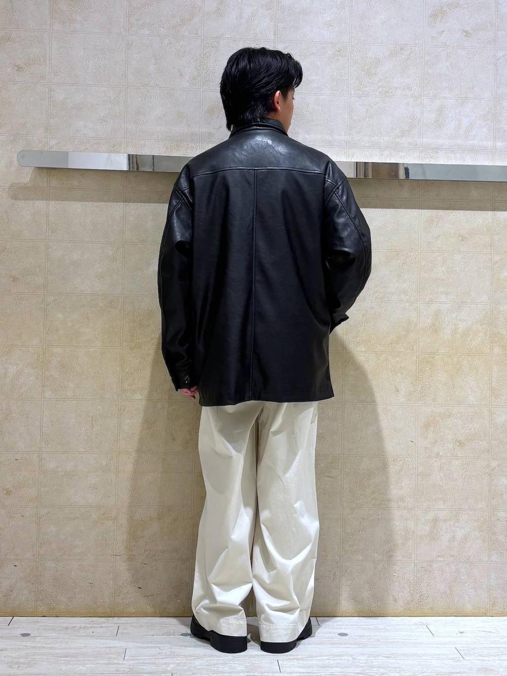 ブラック系のステンカラーコート、ブラック系のドレスシューズ、ホワイト系のチノパンツを着用したメンズの冬コーディネートの6枚目の写真