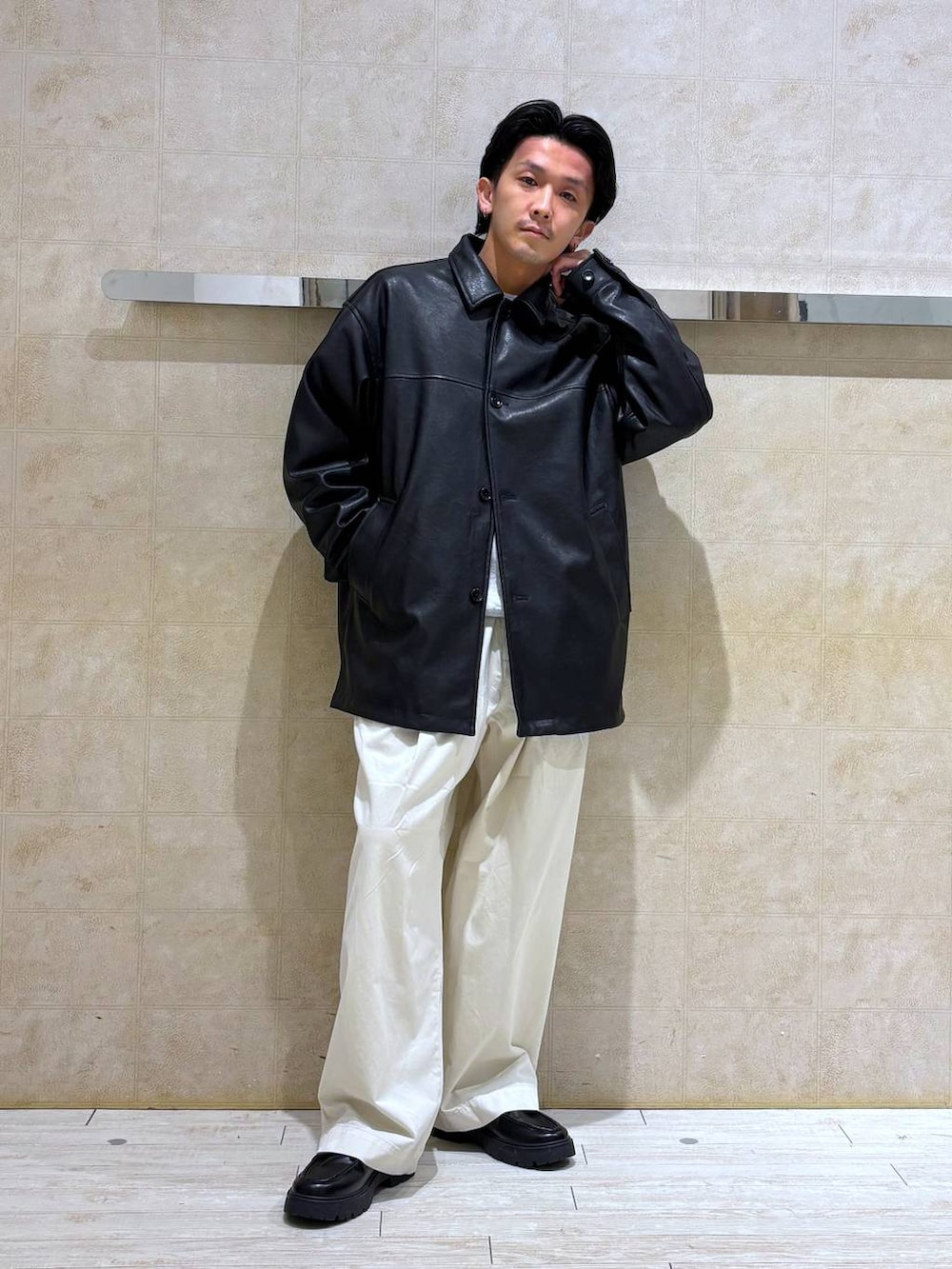 ブラック系のステンカラーコート、ブラック系のドレスシューズ、ホワイト系のチノパンツを着用したメンズの冬コーディネートの2枚目の写真