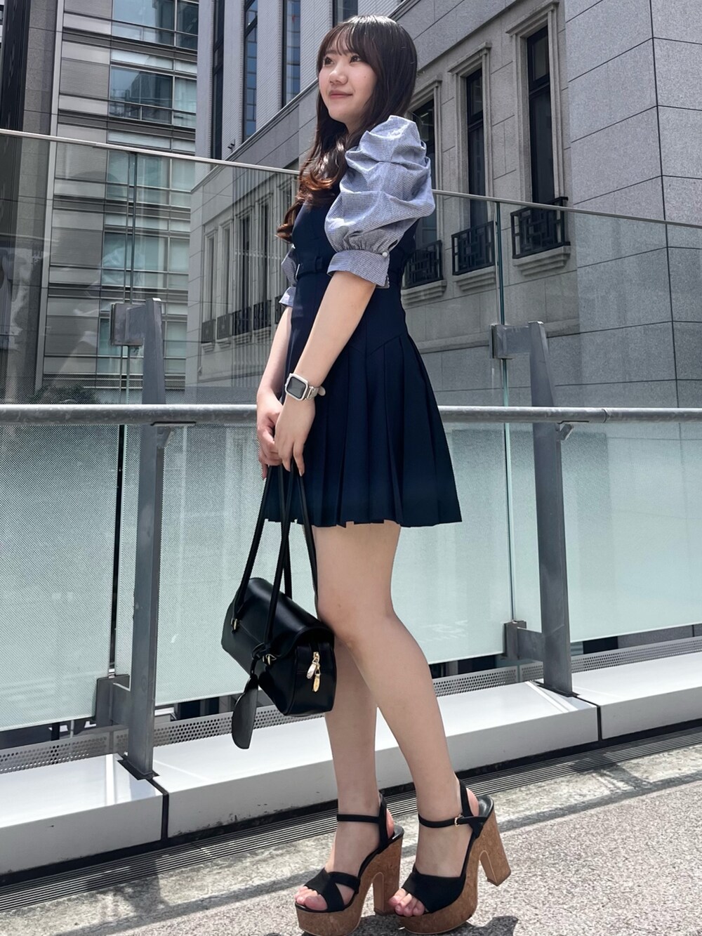 ブルー系のワンピース、ブラック系のハンドバッグ、ブラック系のサンダルを着用したレディースの夏コーディネートの2枚目の写真