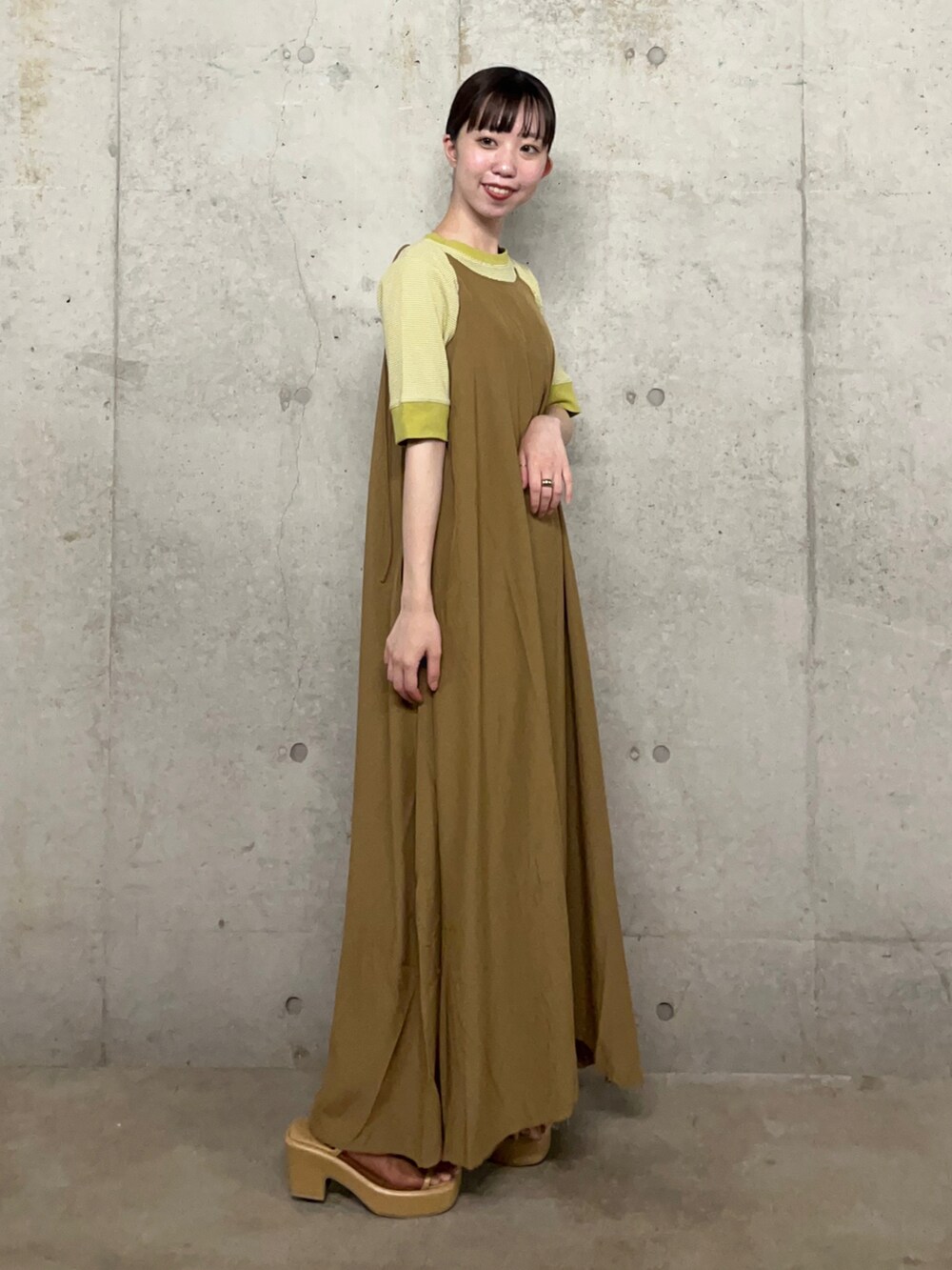 イエロー系のワンピース、グリーン系のTシャツ/カットソー、ベージュ系のサンダルを着用したレディースの夏コーディネートの2枚目の写真