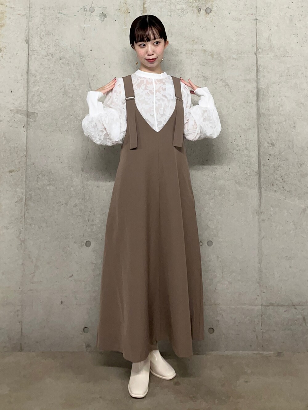 ブラウン系のジャンパースカート、ホワイト系のシャツ/ブラウス、ホワイト系のブーツを着用したレディースの夏コーディネートの2枚目の写真