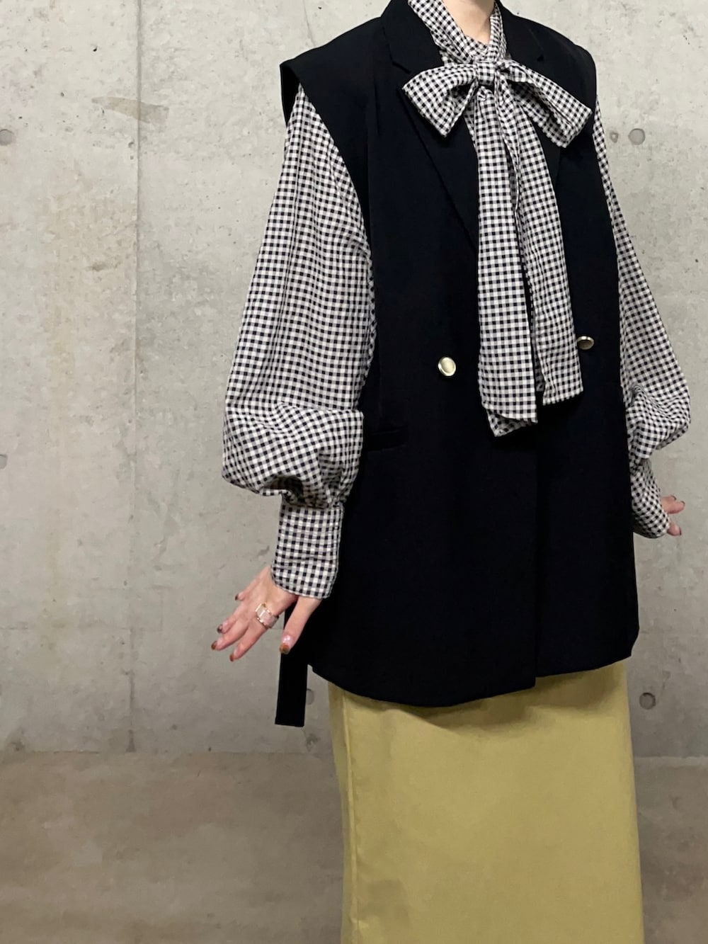 ブラック系のベスト、イエロー系のスカート、ブラック系のシャツ/ブラウスを着用したレディースの秋コーディネートの2枚目の写真