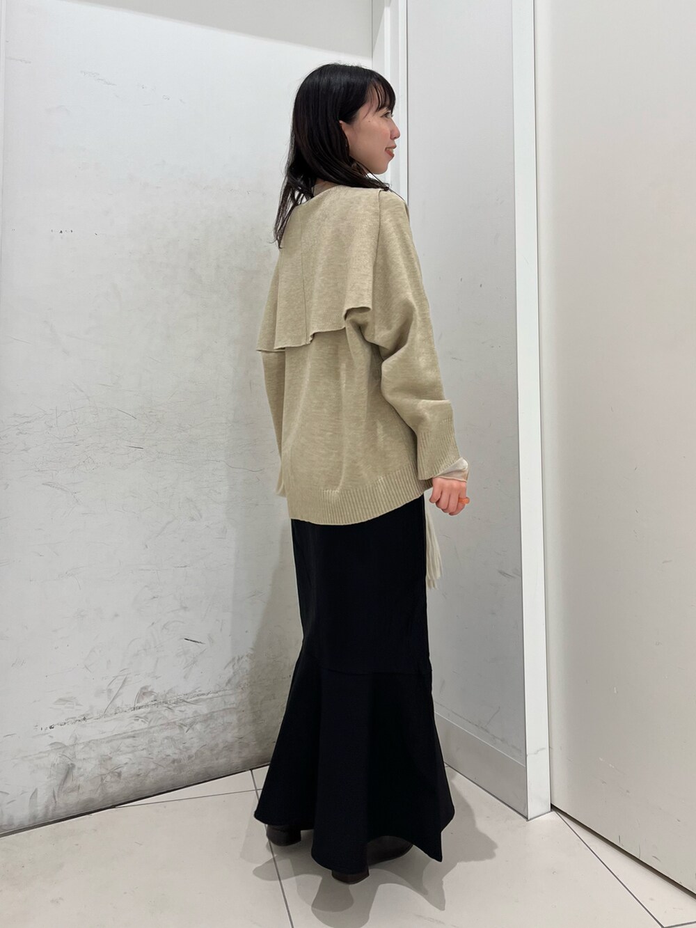 ブラウン系のブーツ、ベージュ系のニット/セーター、ブラック系のスカートを着用したレディースの冬コーディネートの2枚目の写真