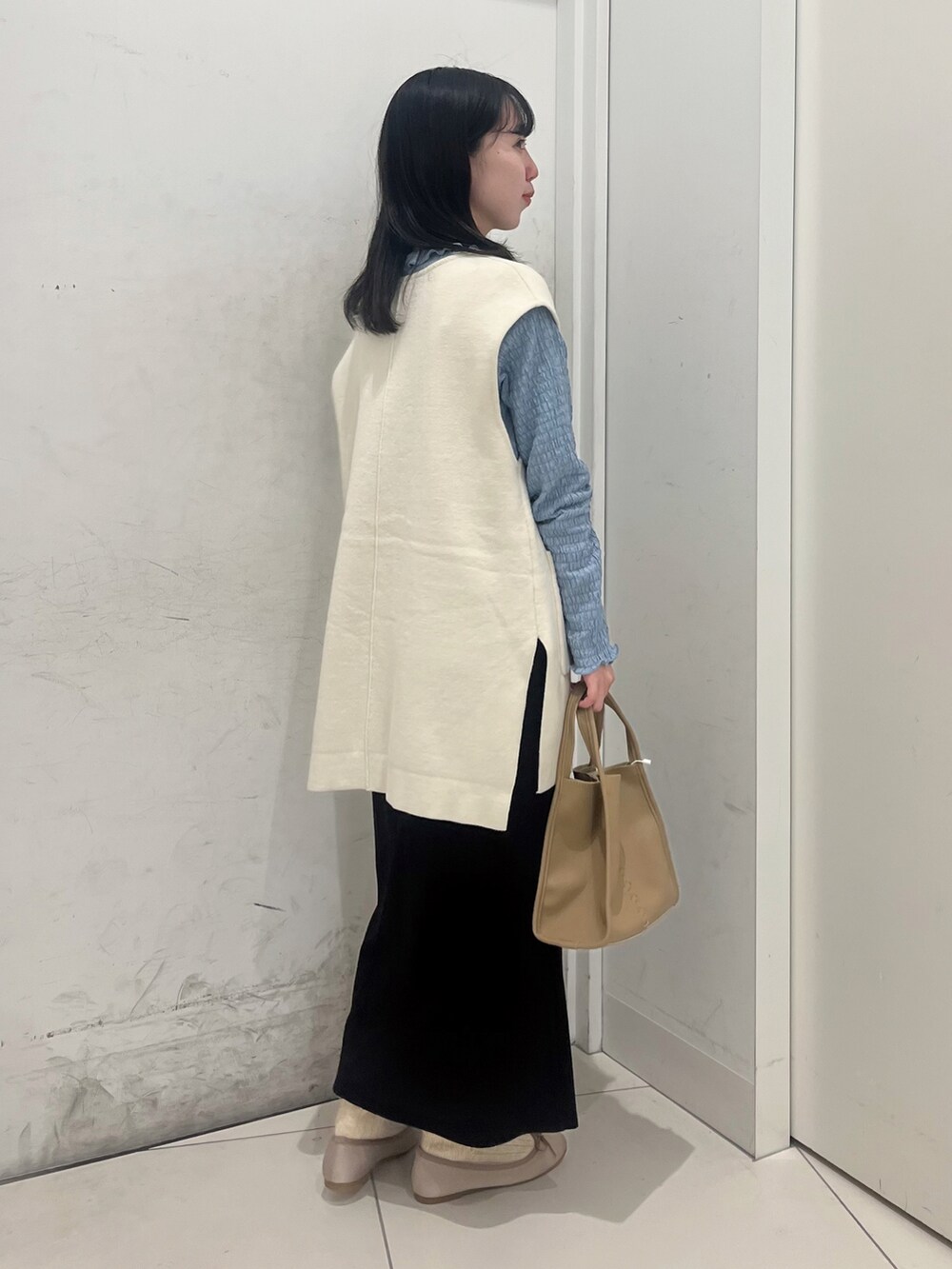 ベージュ系のショルダーバッグ、ブルー系のTシャツ/カットソー、ブラック系のスカートを着用したレディースの冬コーディネートの2枚目の写真