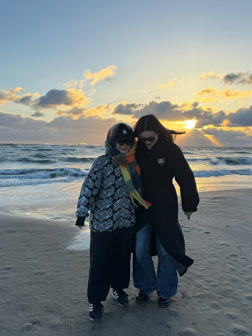 ブラック系のステンカラーコート、ブルー系のデニムパンツ、ブラック系のブーツを着用したレディースの冬コーディネートの2枚目の写真