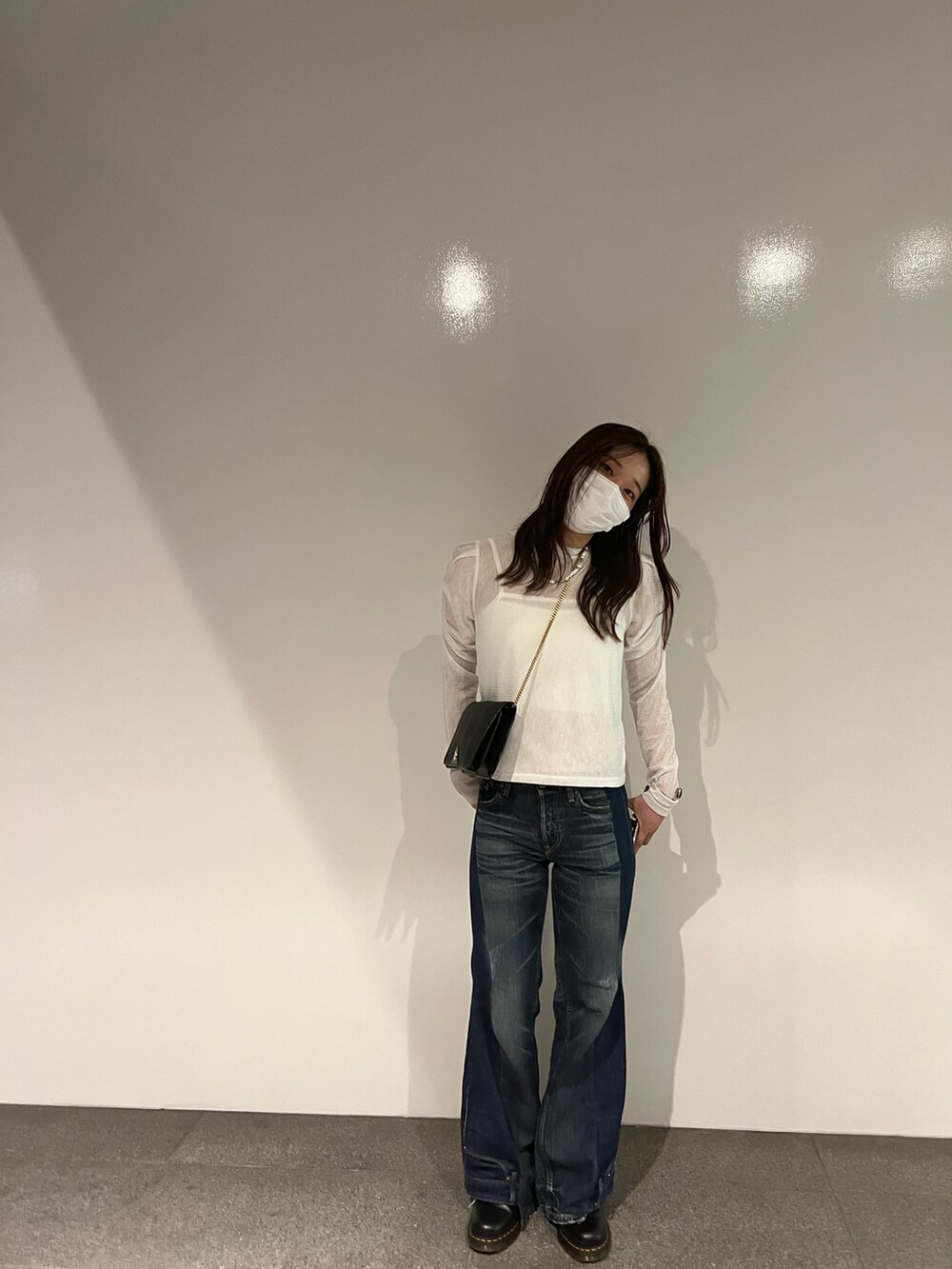 ブルー系のデニムパンツ、ホワイト系のTシャツ/カットソー、ブラック系のバッグを着用したレディースの秋コーディネートの3枚目の写真